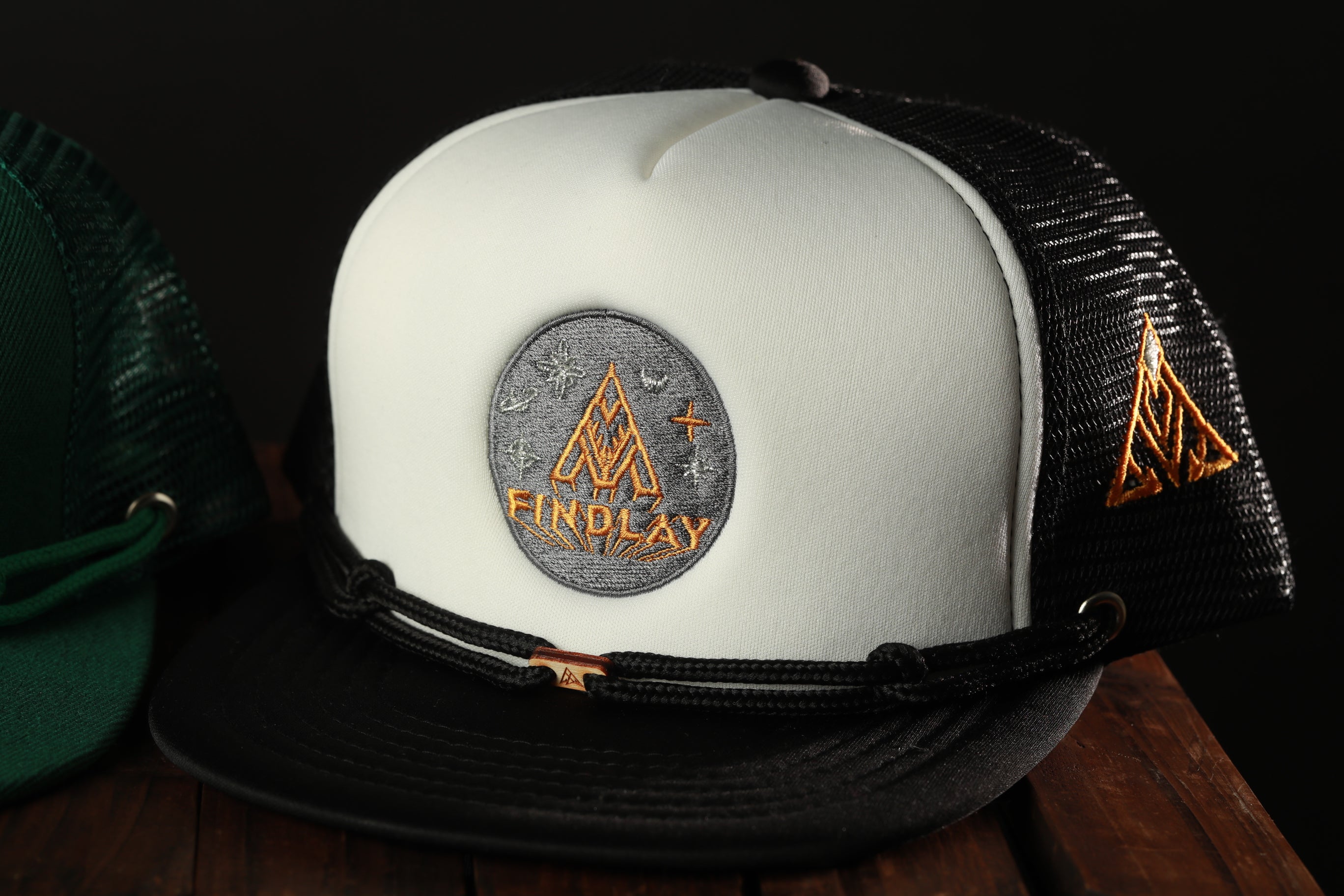 A white baseball cap with a black brim and a black band, featuring a logo on the front.