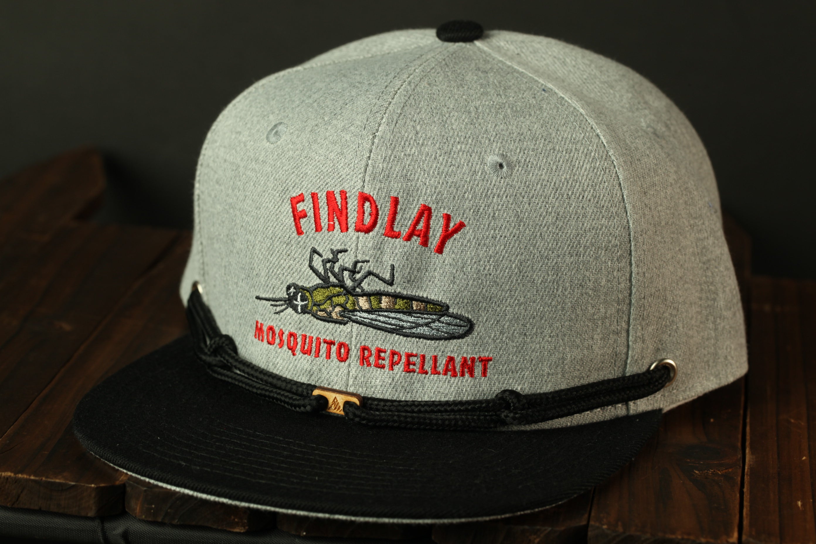 A gray baseball cap with a black brim and a red and white logo on the front, which says "FINDLAY MOSQUITO REPELLANT".
