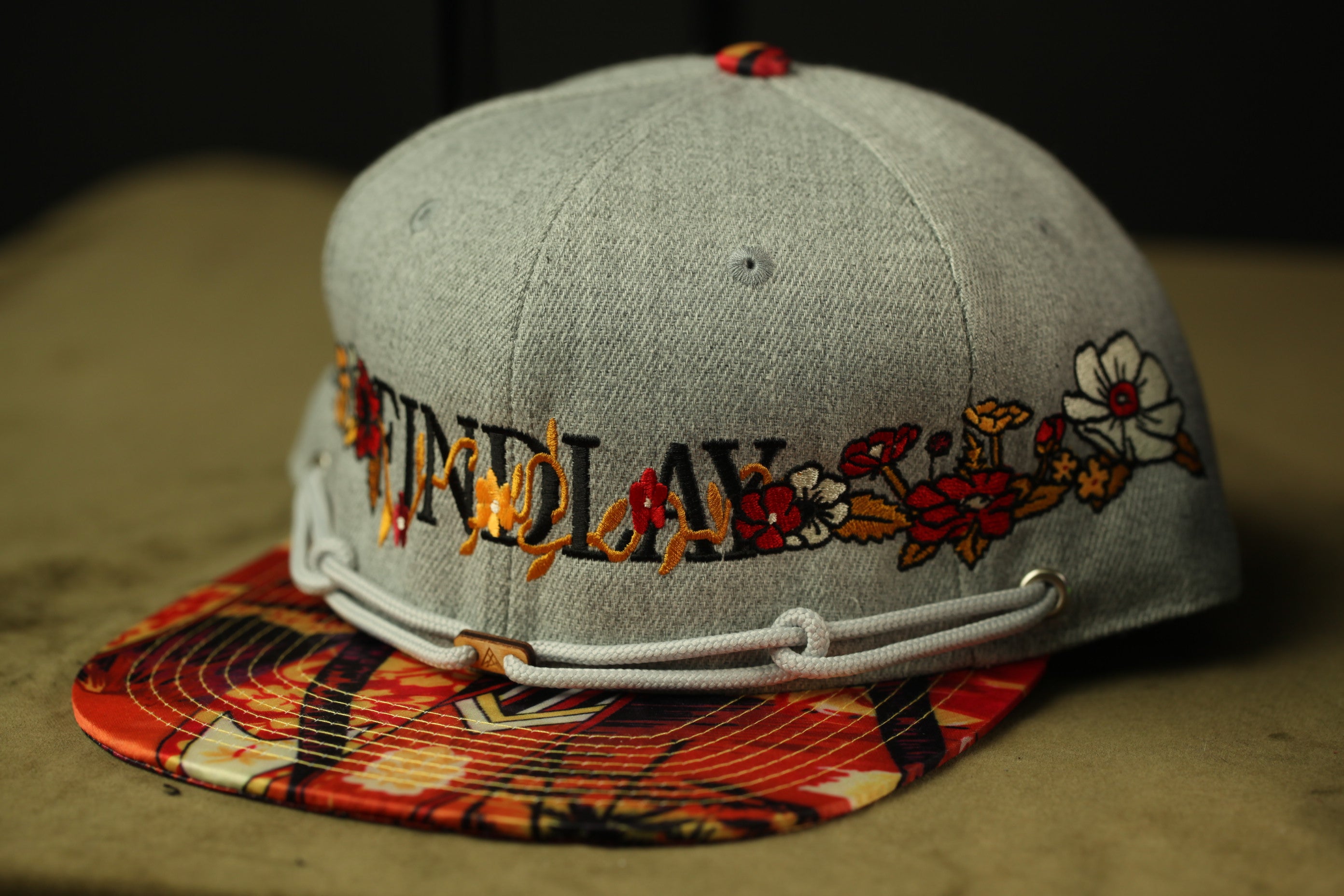 A gray baseball cap with a floral pattern and the word "FLORAL" printed on it.