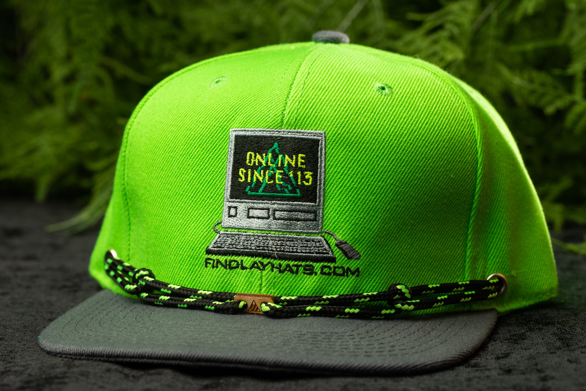 A neon green baseball cap with a graphic of a computer and the text "Online Since 13" printed on it, along with the website "FindlayHats.com".