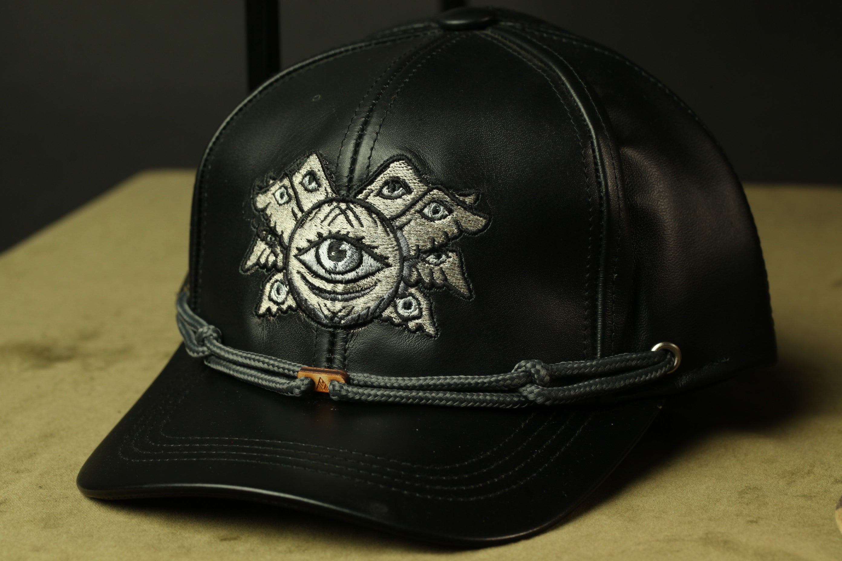 A black baseball cap with an eye design on the front.