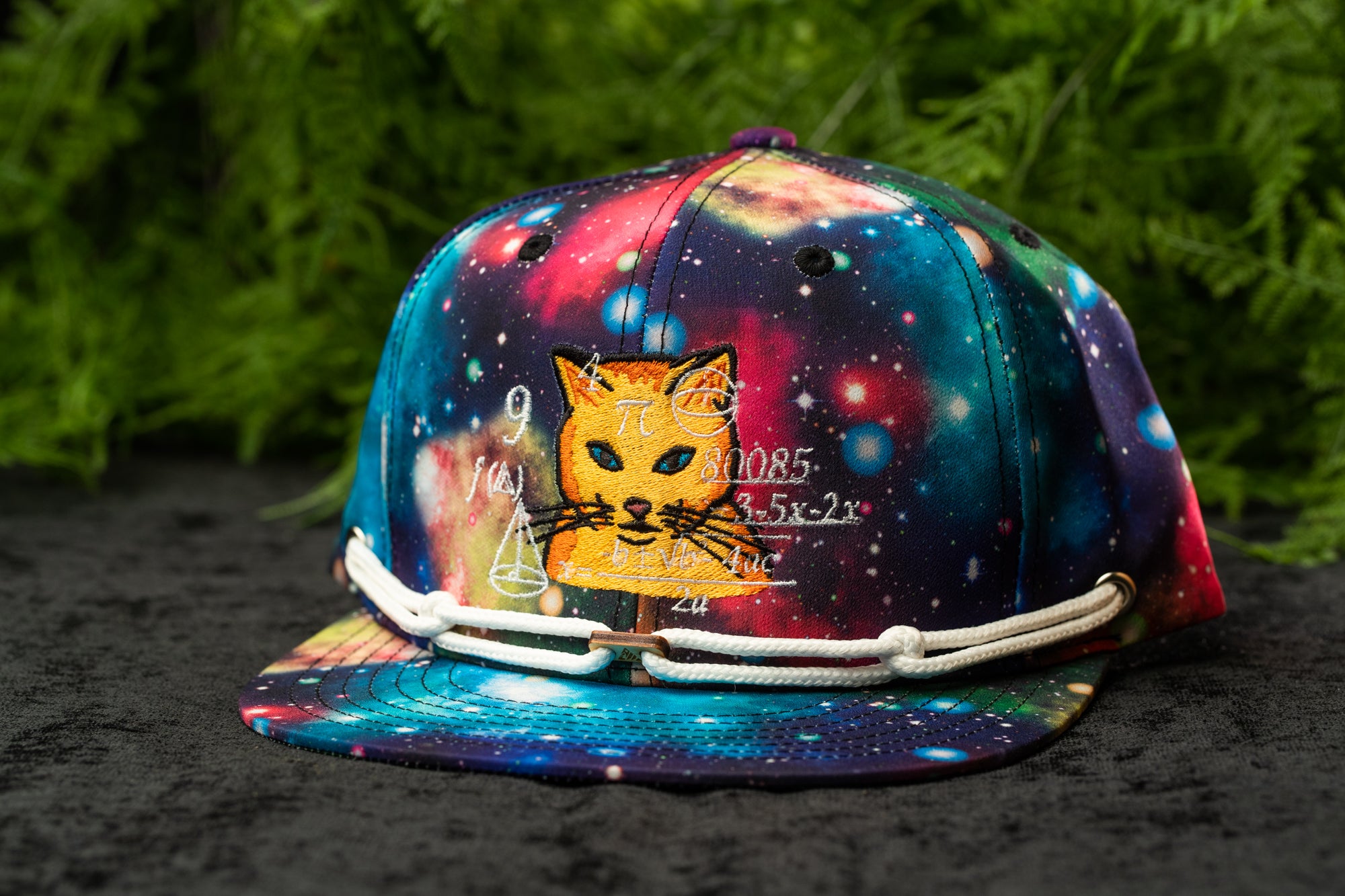 A colorful, patterned baseball cap with a cat design and a space-themed background.