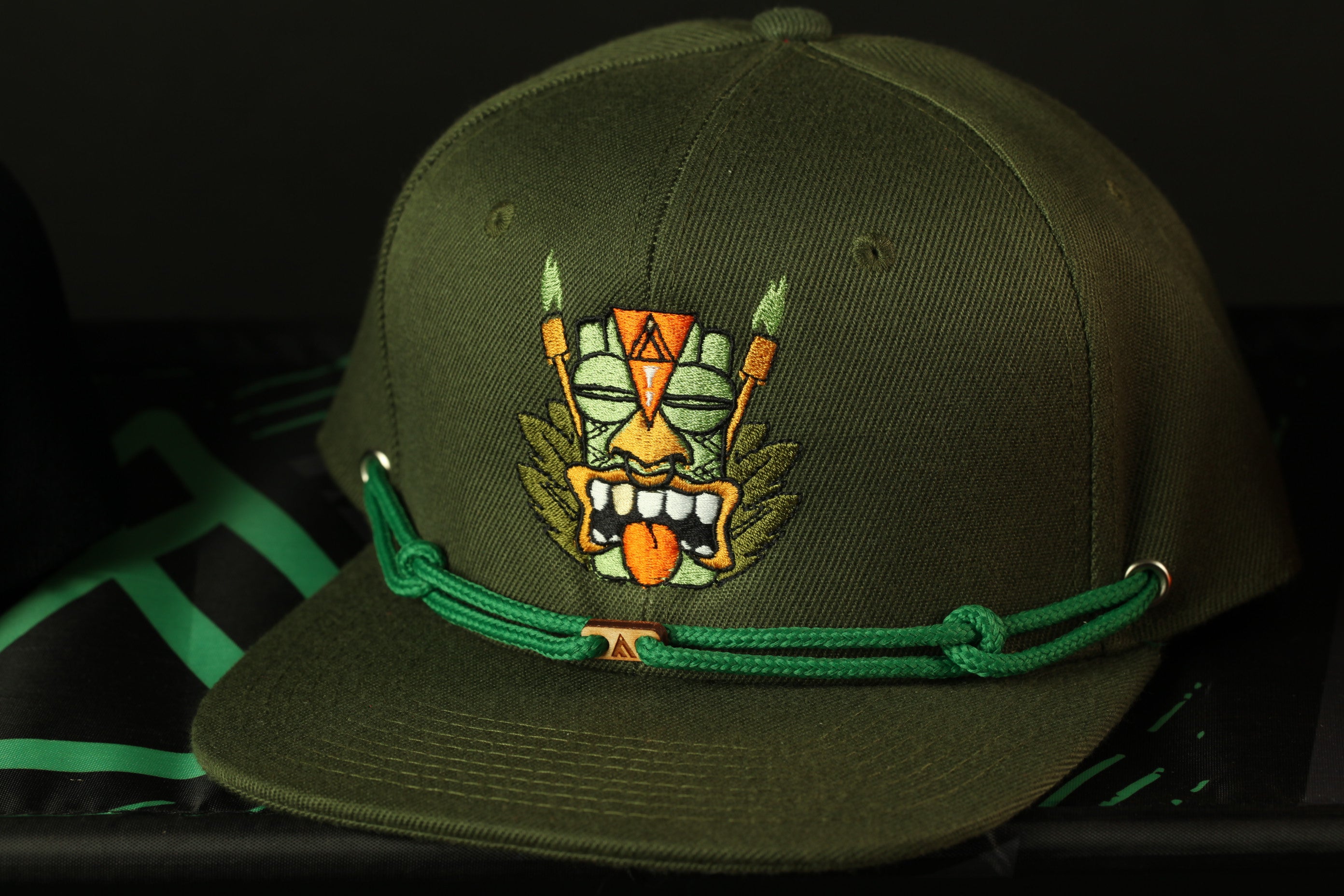 A dark green baseball cap with a colorful, cartoonish design on the front.