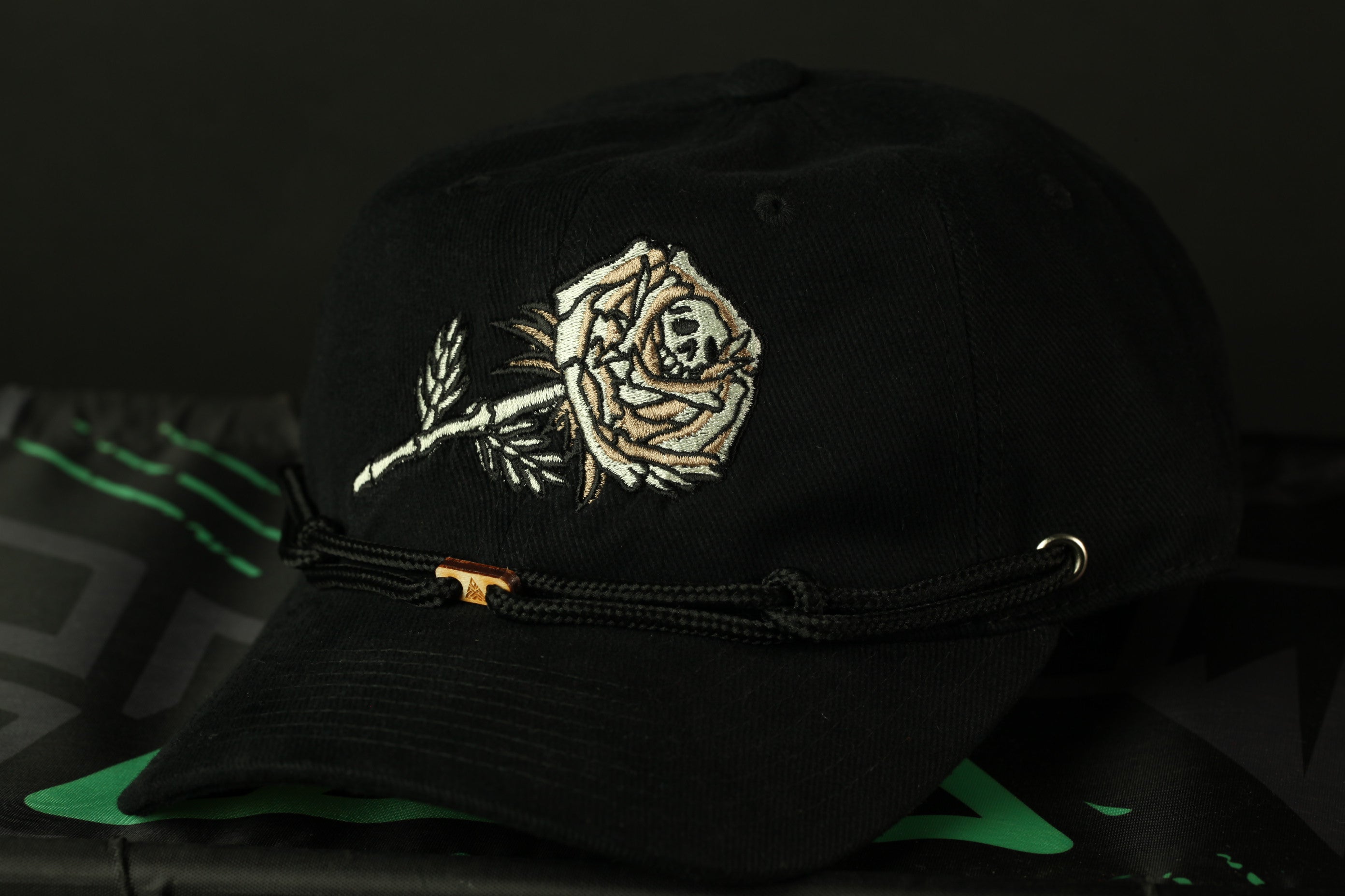 A black baseball cap with a white embroidered rose design on the front.