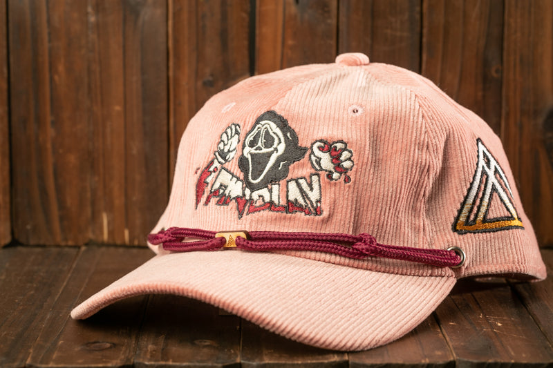 A pink baseball cap with a graphic design featuring a ghost or skeleton figure and the word "FAMOUS" printed on it.