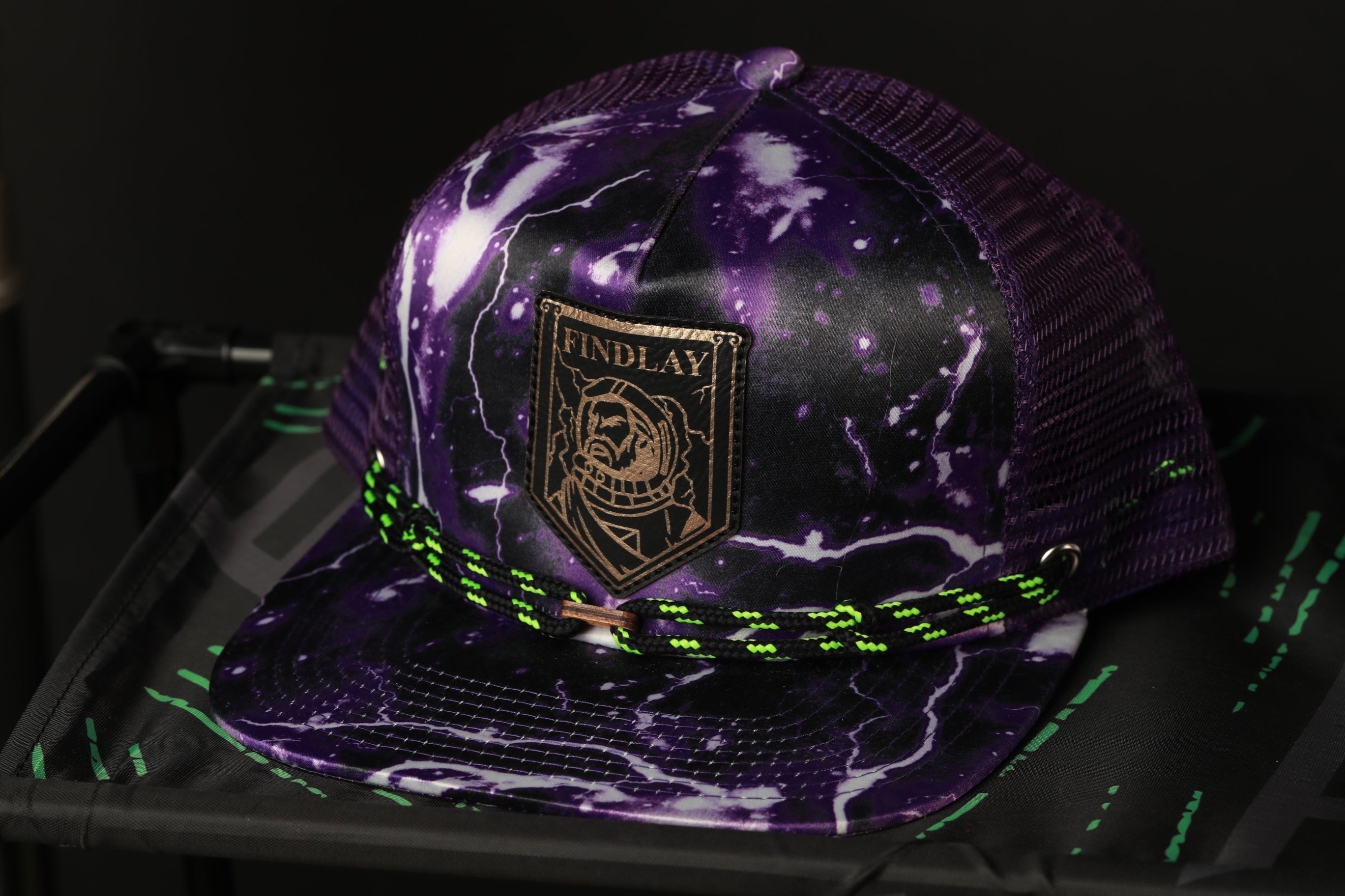 A purple baseball cap with a black and white lightning bolt design, featuring a gold-colored patch with a graphic of a person's face.
