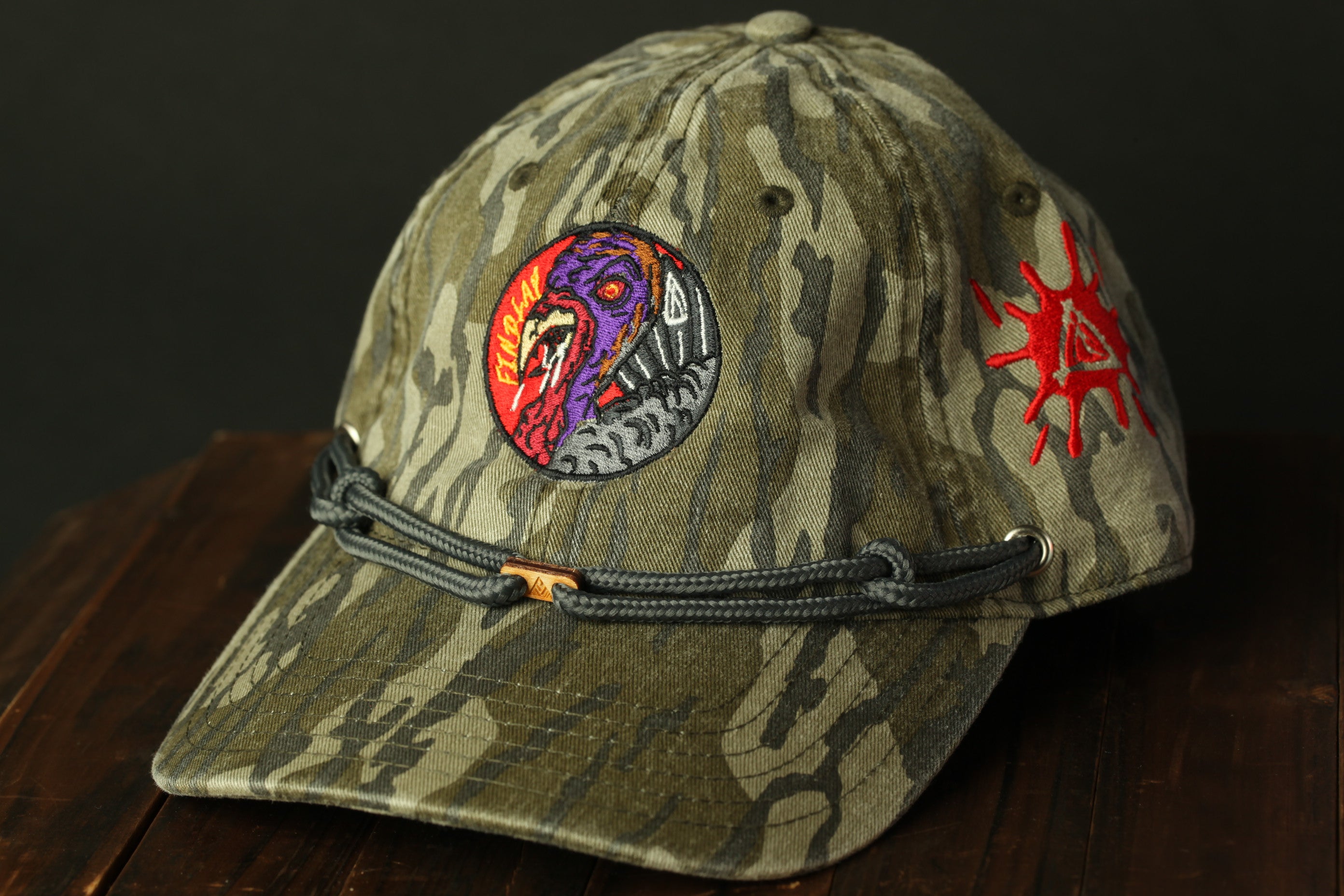 A camouflage baseball cap with a colorful, abstract design on the front.