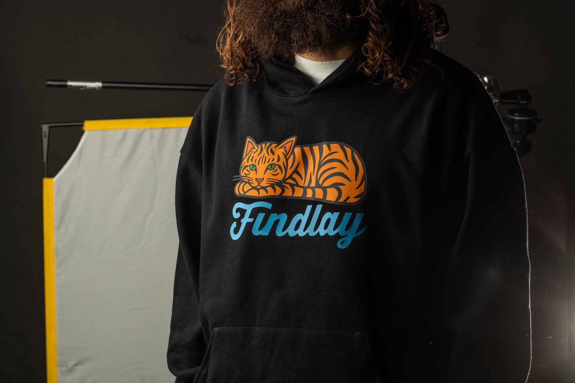 A person wearing a black hoodie with a graphic of a tiger and the word "Findlay" printed on it.