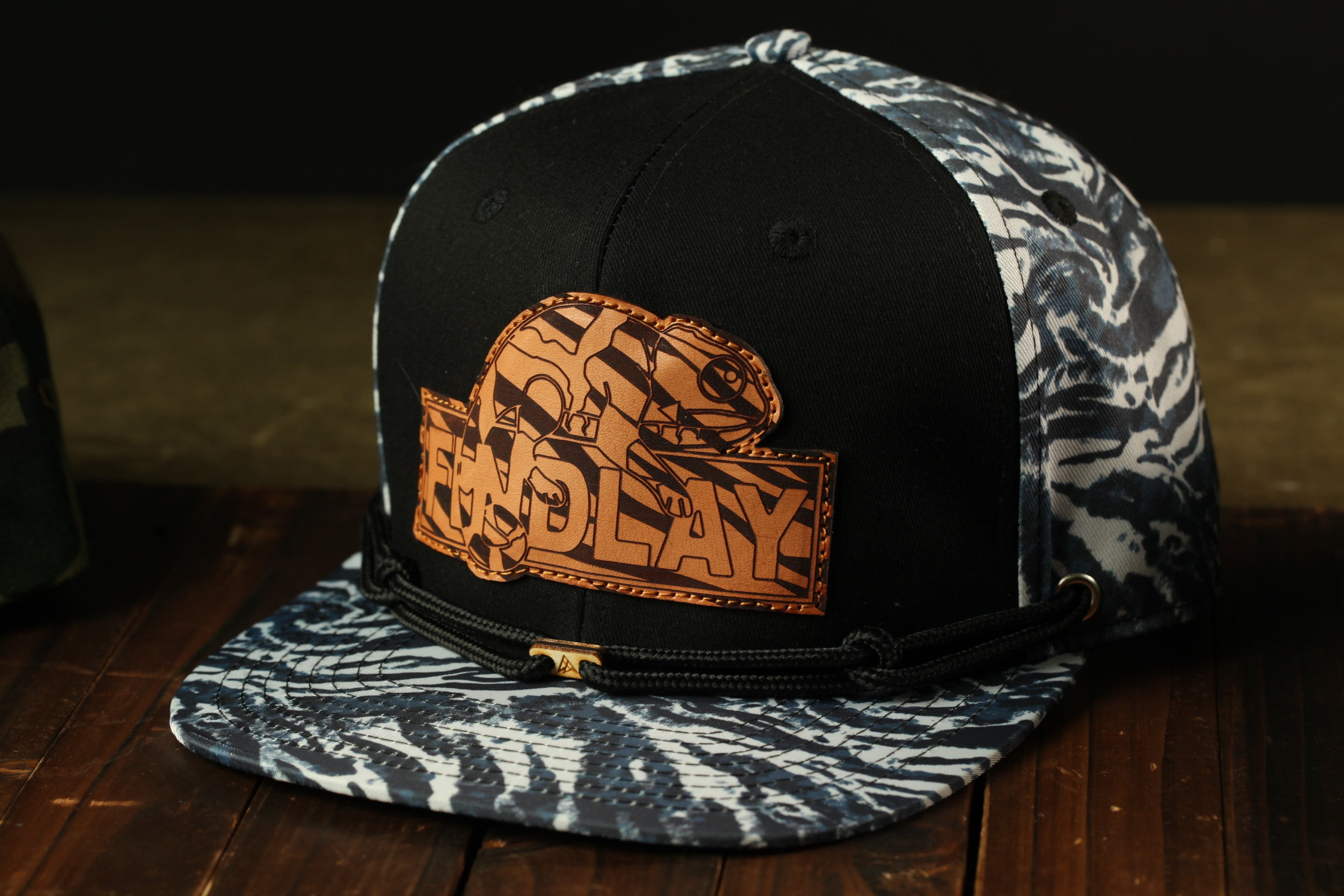 A black and white patterned baseball cap with a zebra print design and a logo on the front.