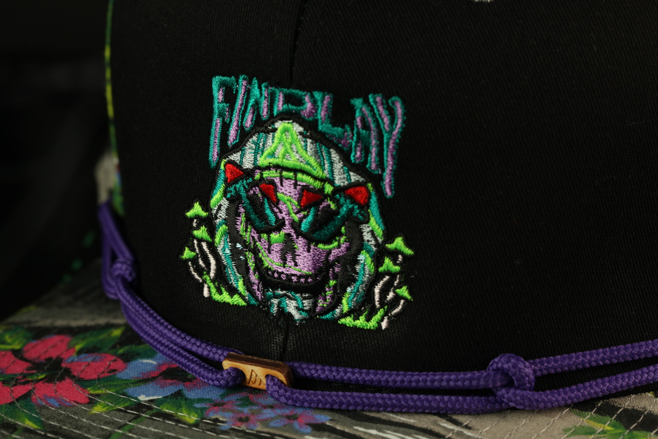 a close-up view of a black baseball cap with a colorful, embroidered design on the front.