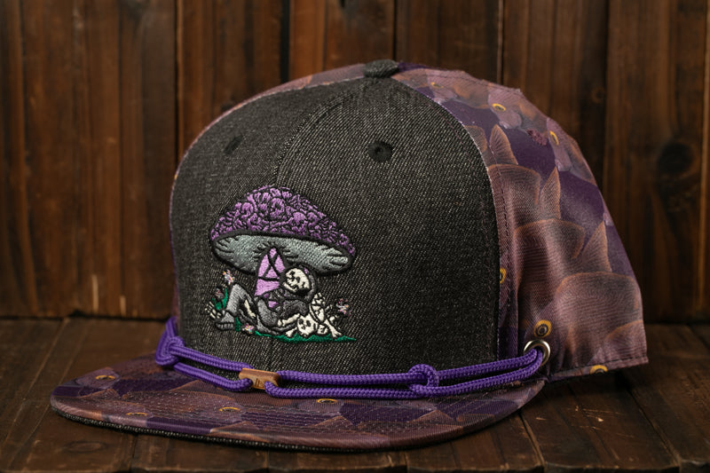 A black baseball cap with a purple and purple floral pattern, featuring an embroidered mushroom design on the front.