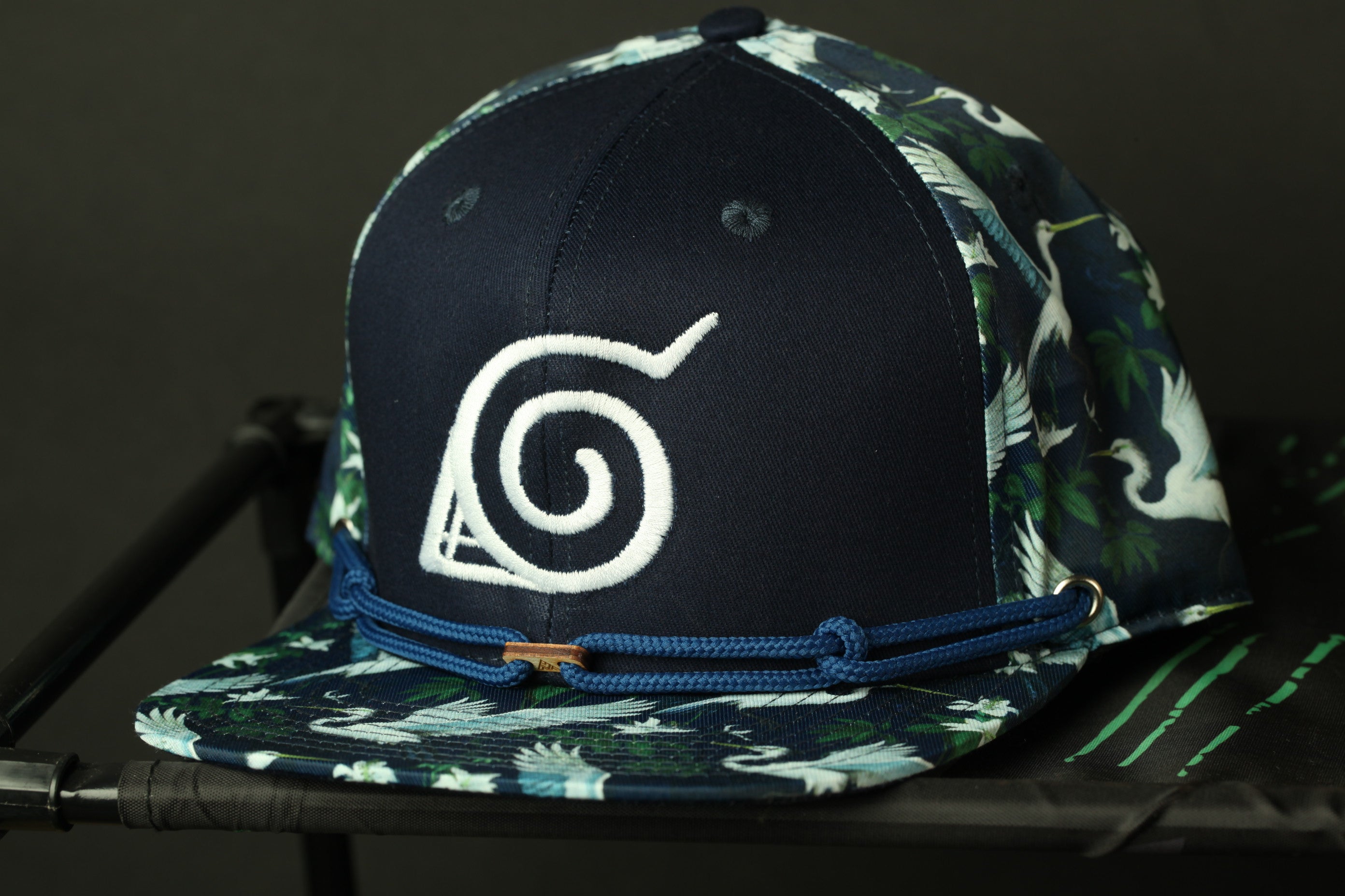 A navy blue baseball cap with a white spiral logo on the front, sitting on a black surface.