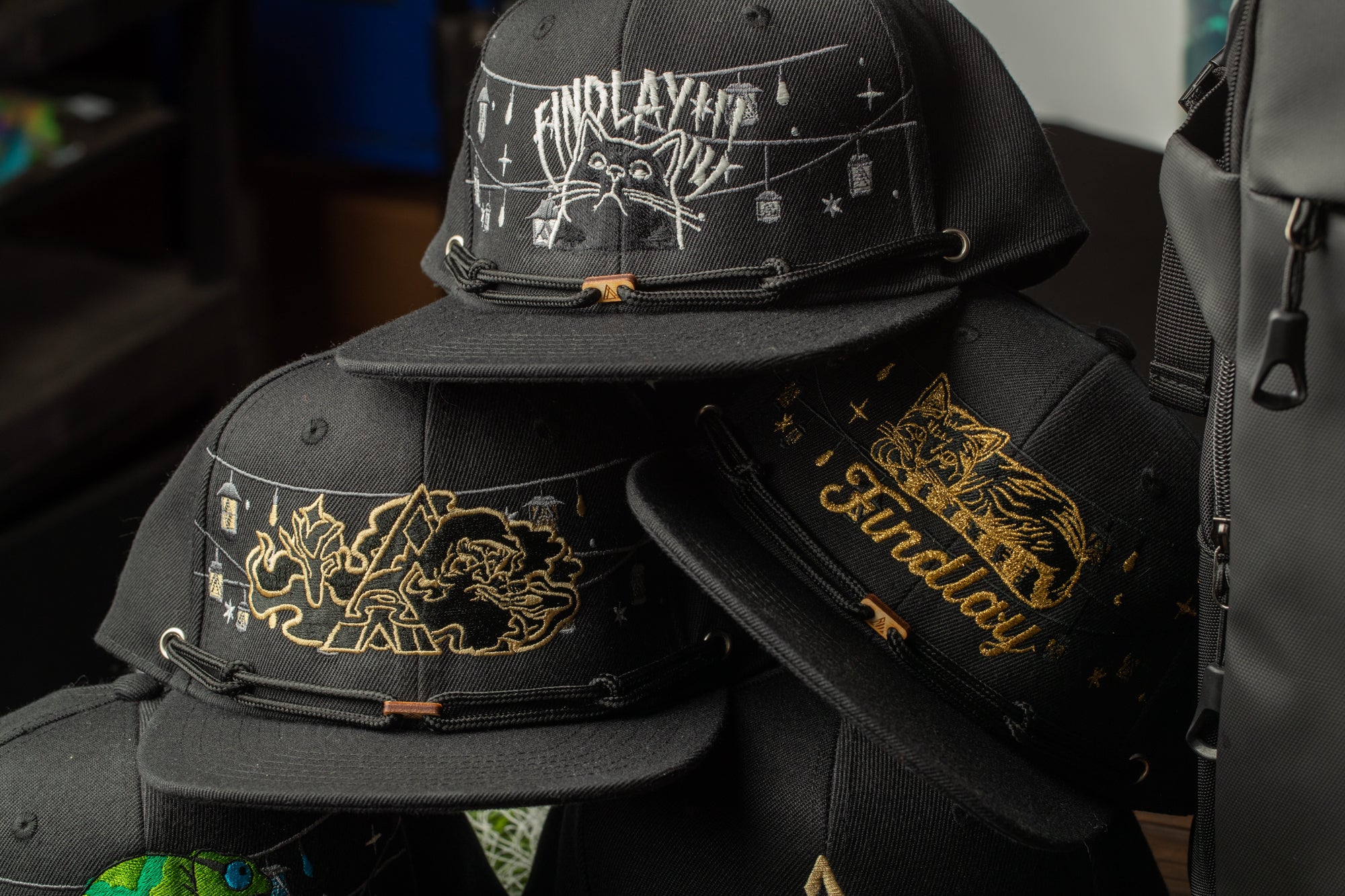A collection of black baseball caps with various designs and text, including one with the word "FINDlay" printed on it.
