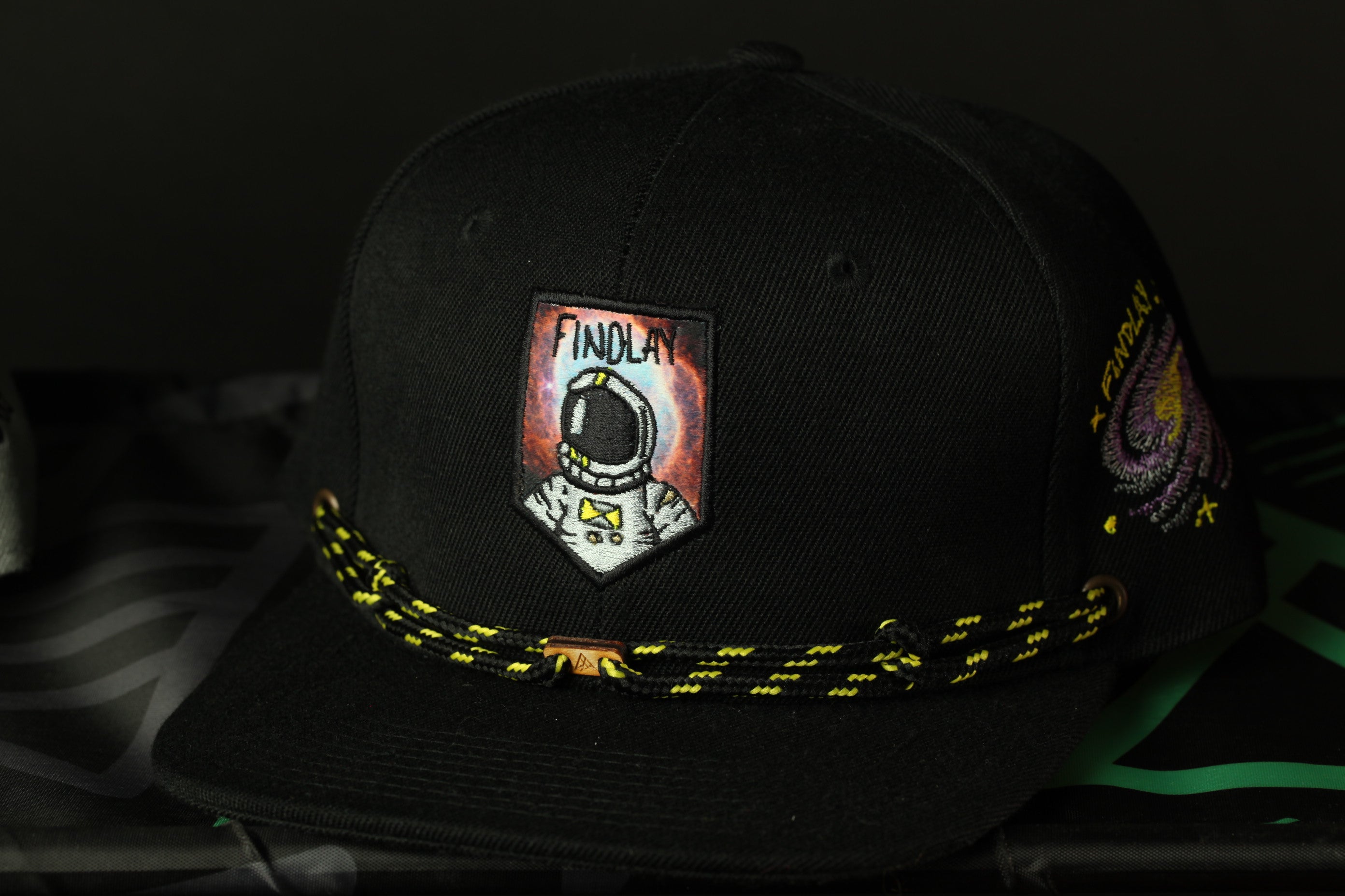 A black baseball cap with a patch featuring an astronaut and the word "FINDOLAY" on it.