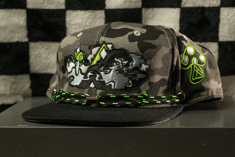 A camouflage baseball cap with a green and black design, featuring a mushroom-like symbol on the side.