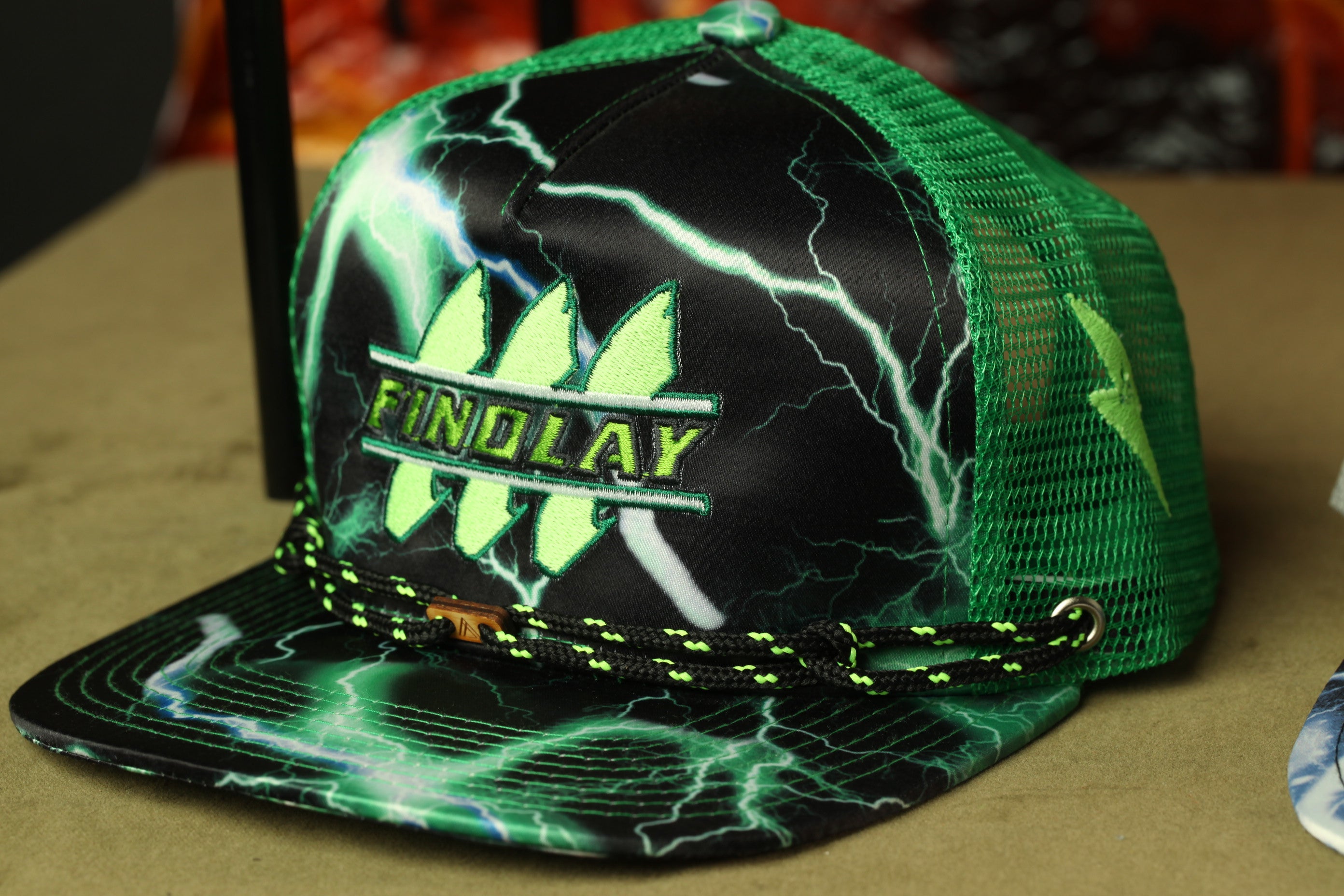 A green and black baseball cap with a lightning bolt design, featuring the word "FINDlay" on the front.