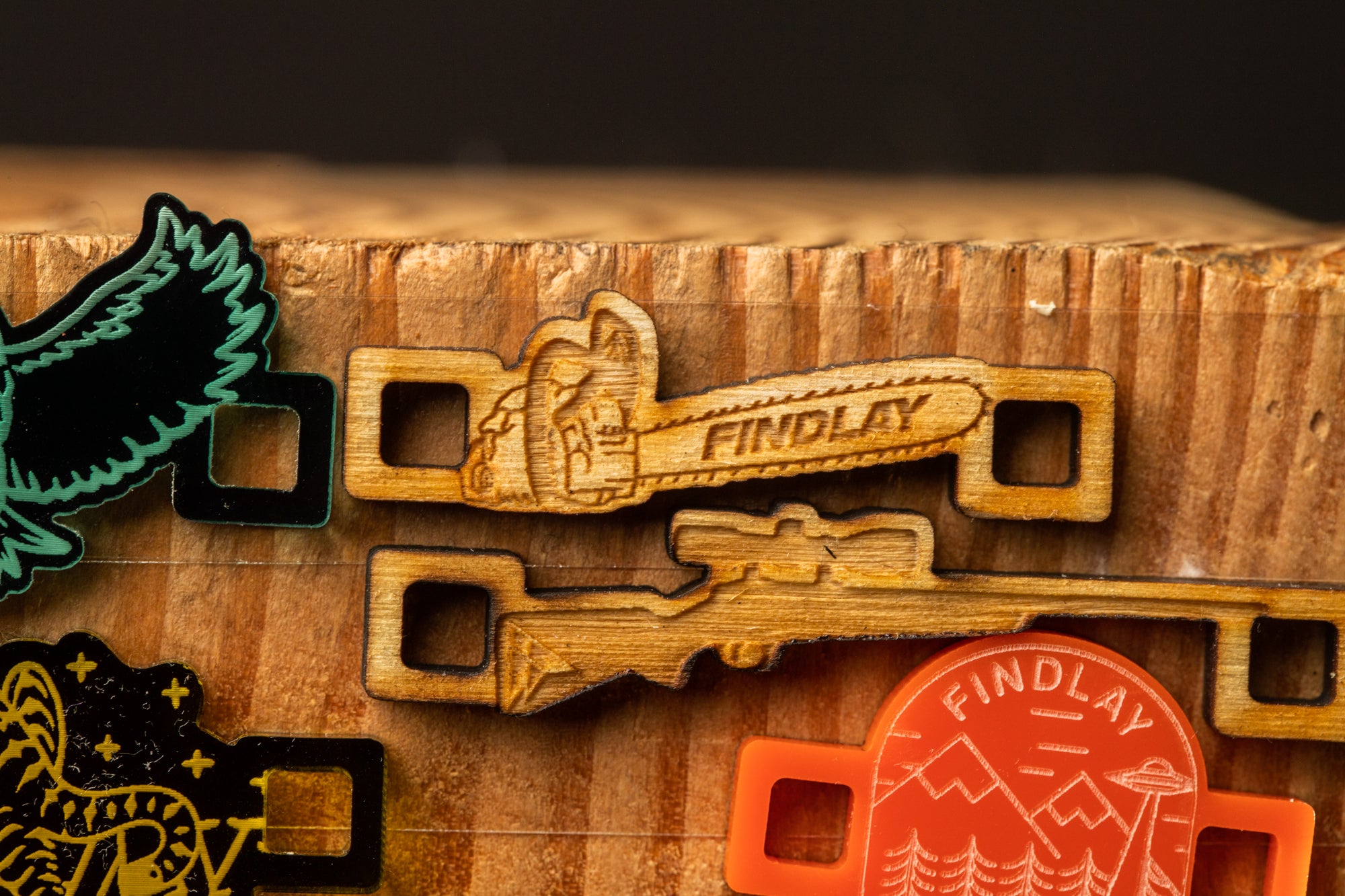 a collection of wooden keychains with various designs, including a keychain with a bird and a keychain with a chainsaw.