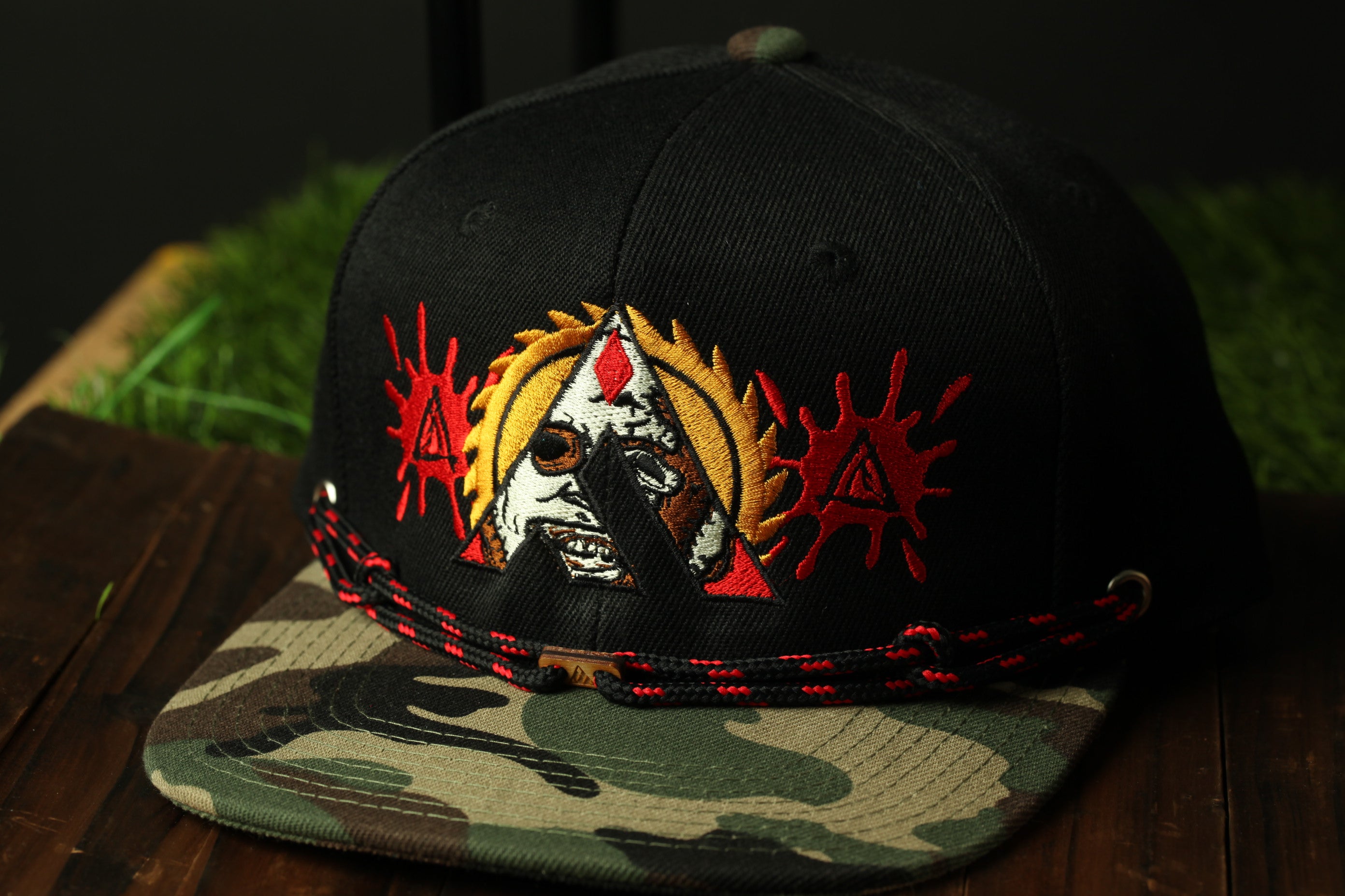 A black baseball cap with a camouflage pattern and a skull-like design on the front.