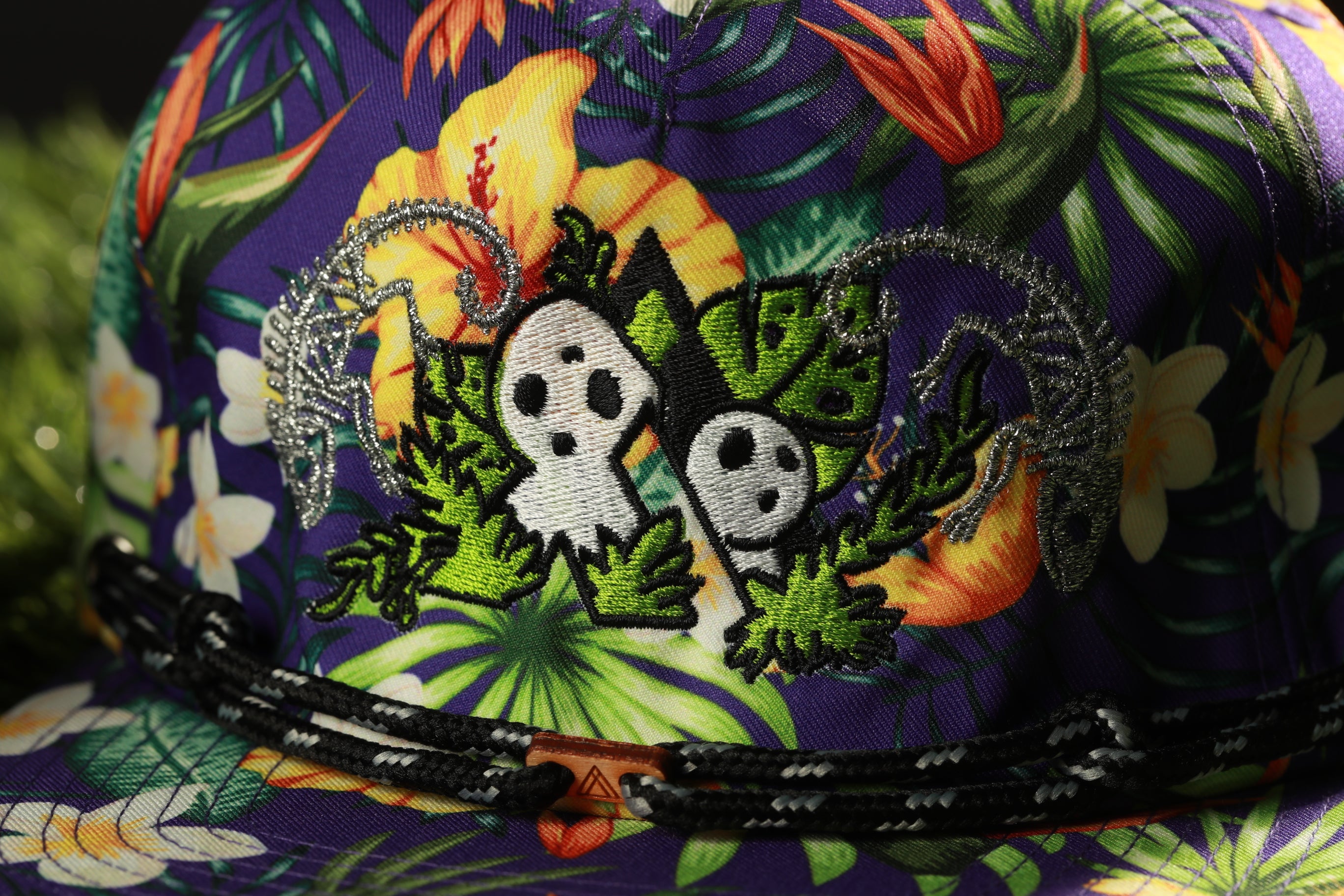 A close-up view of a colorful, patterned hat with a floral design and two small white figures with black eyes and noses.