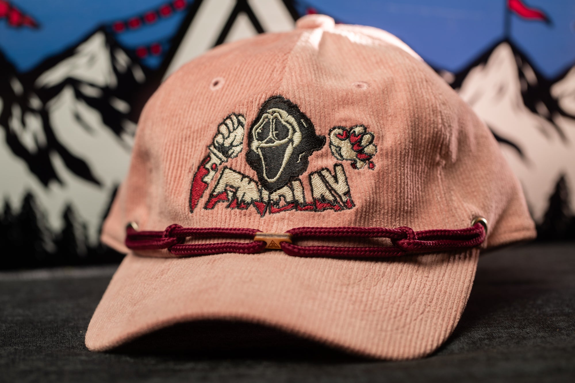 A pink baseball cap with a graphic design on it, featuring a skull and crossbones symbol, is shown in the image.