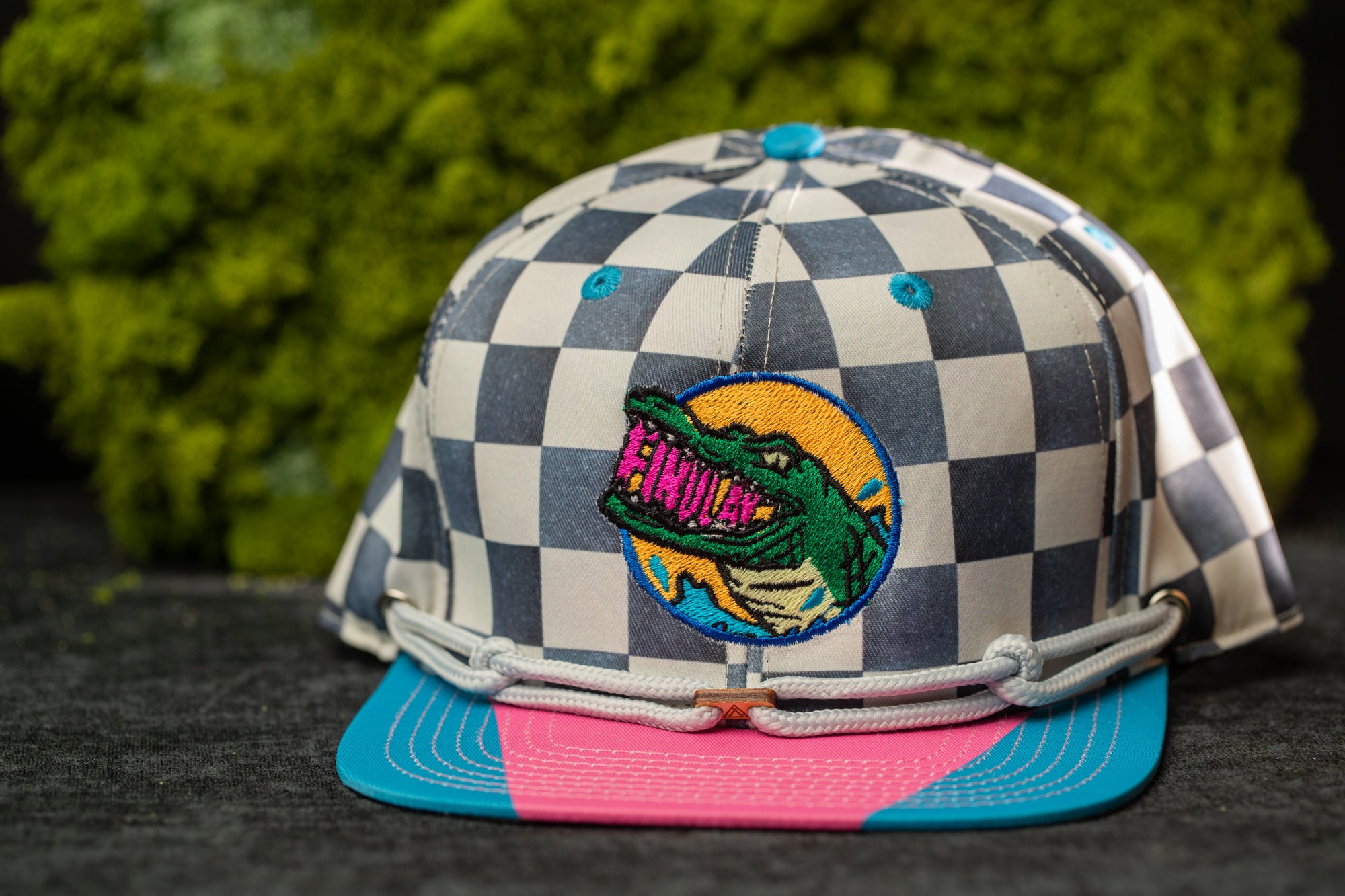 A colorful baseball cap with a checkered pattern and a graphic of a crocodile on the front.