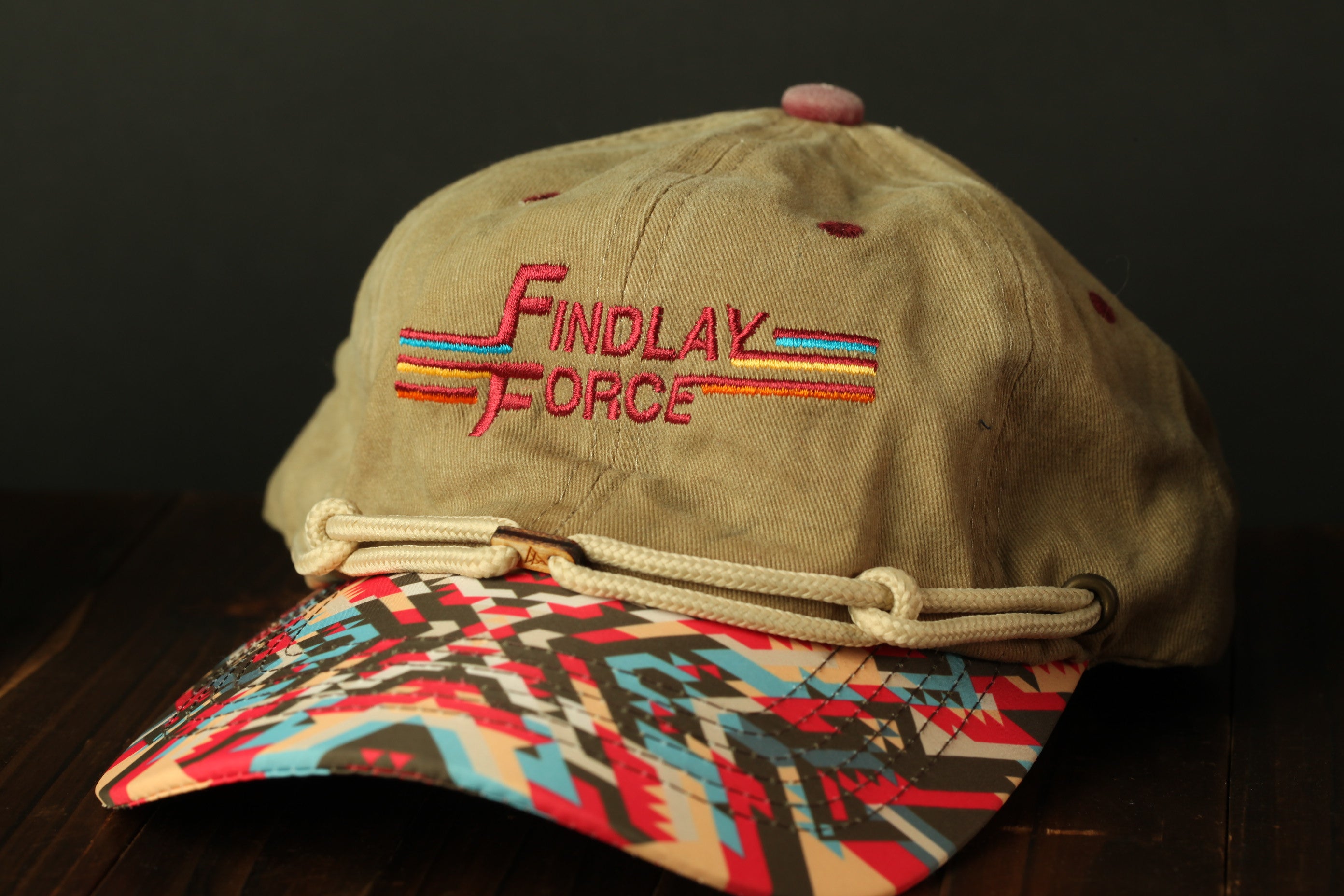 A beige baseball cap with a colorful geometric pattern and the text "Findlay Force" embroidered on it.