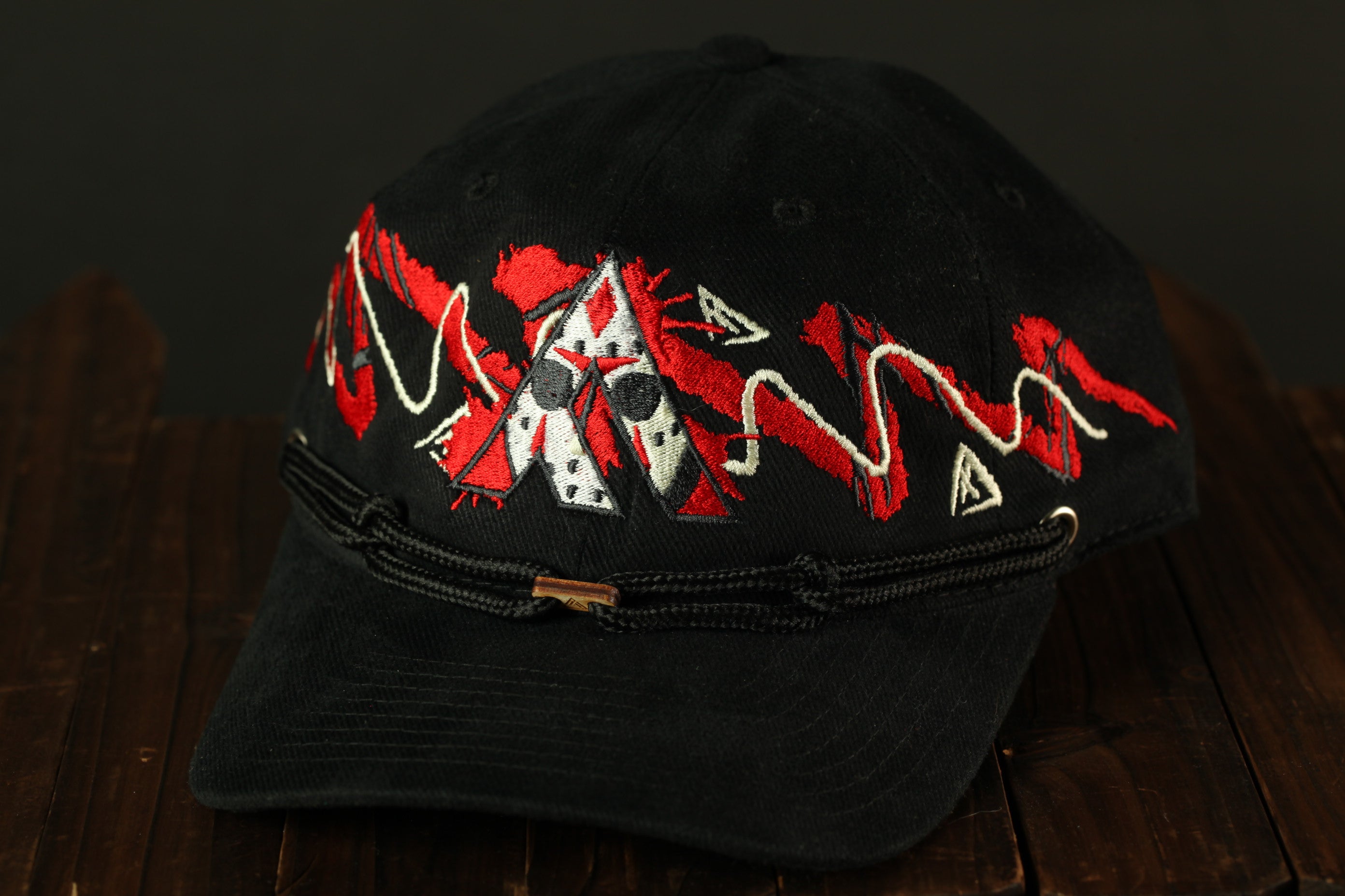 A black baseball cap with red and white embroidered designs on the front.