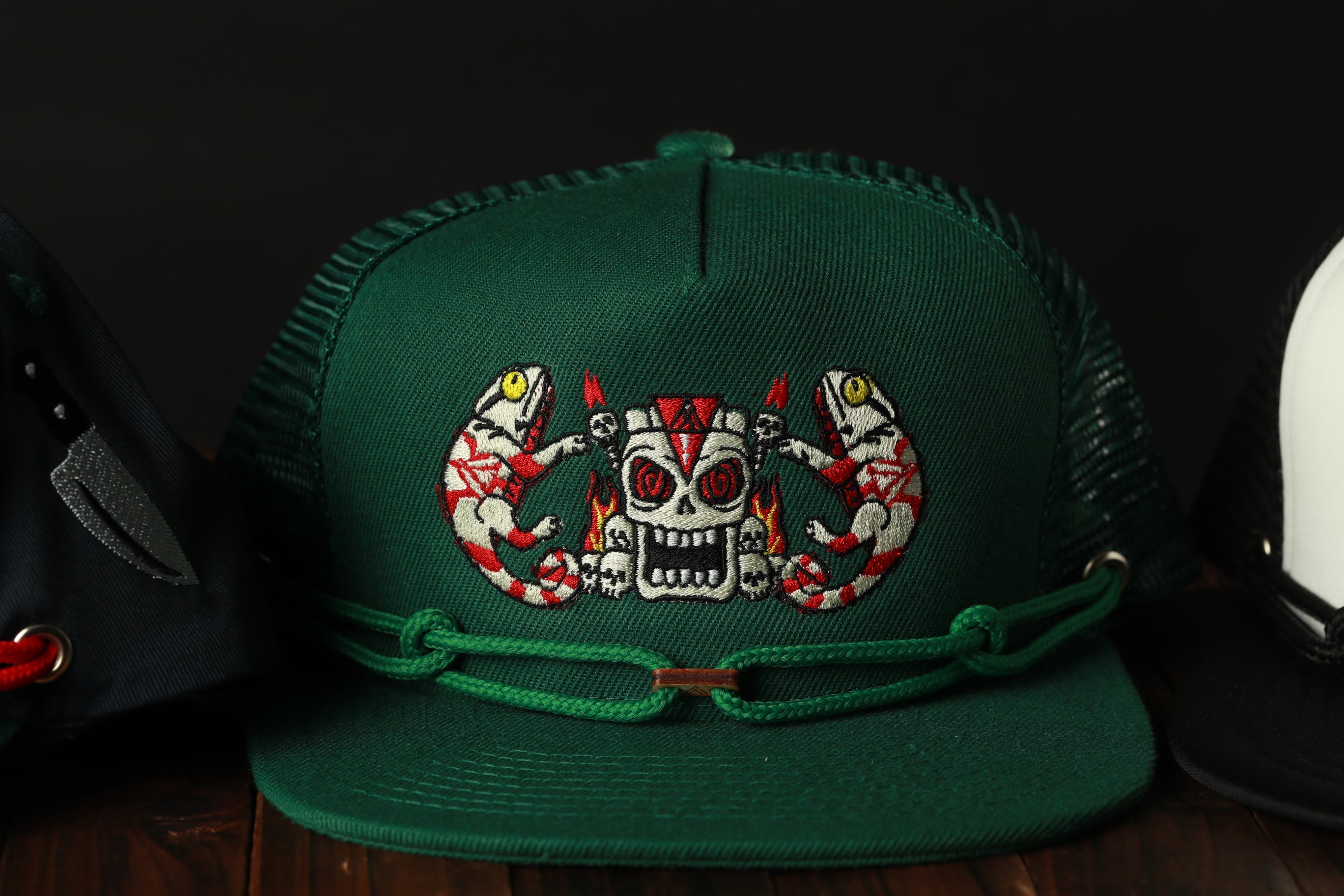 A green baseball cap with a skull and crossbones design on the front, along with a green band and a black band.