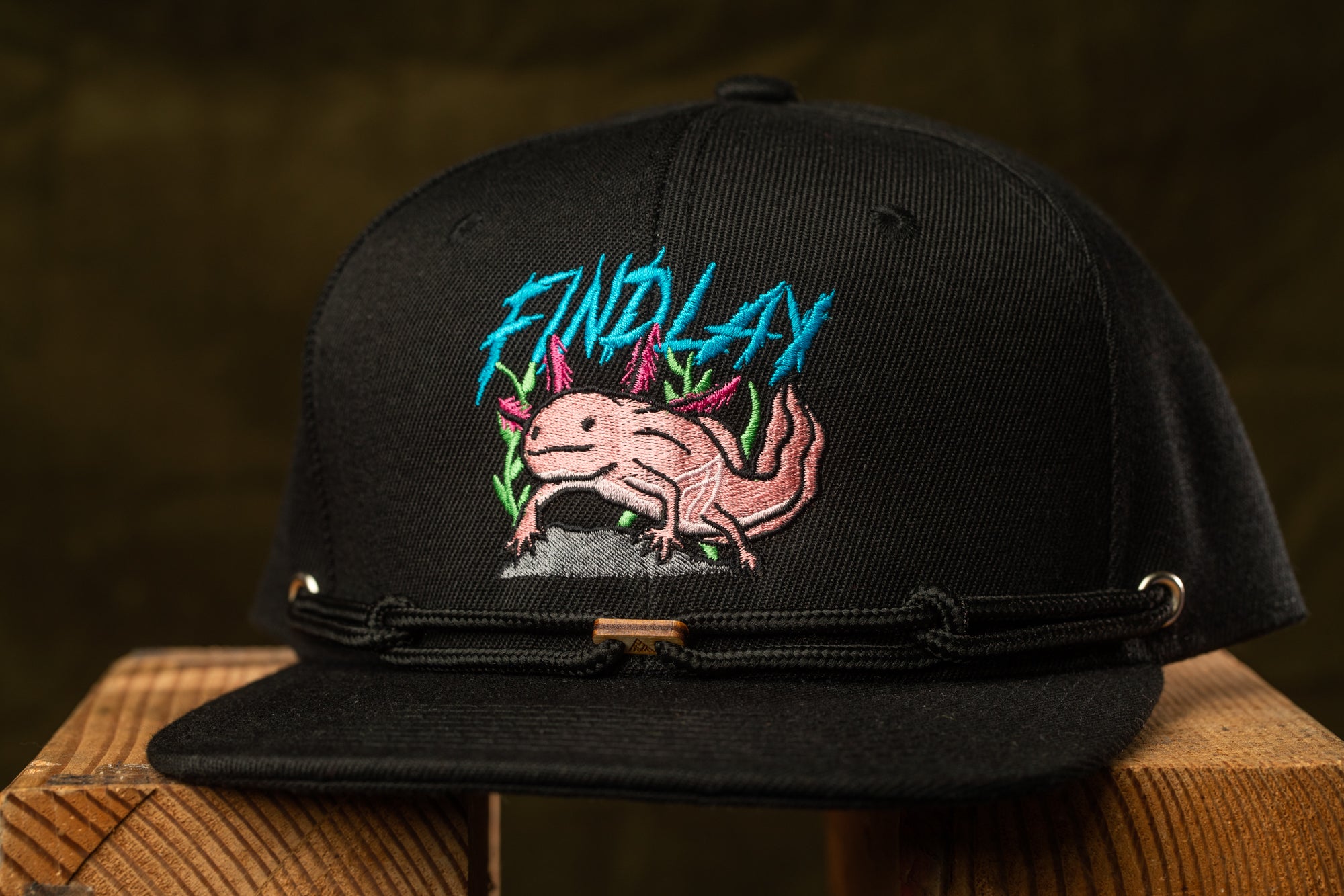 A black baseball cap with a graphic of a pink alligator on the front.