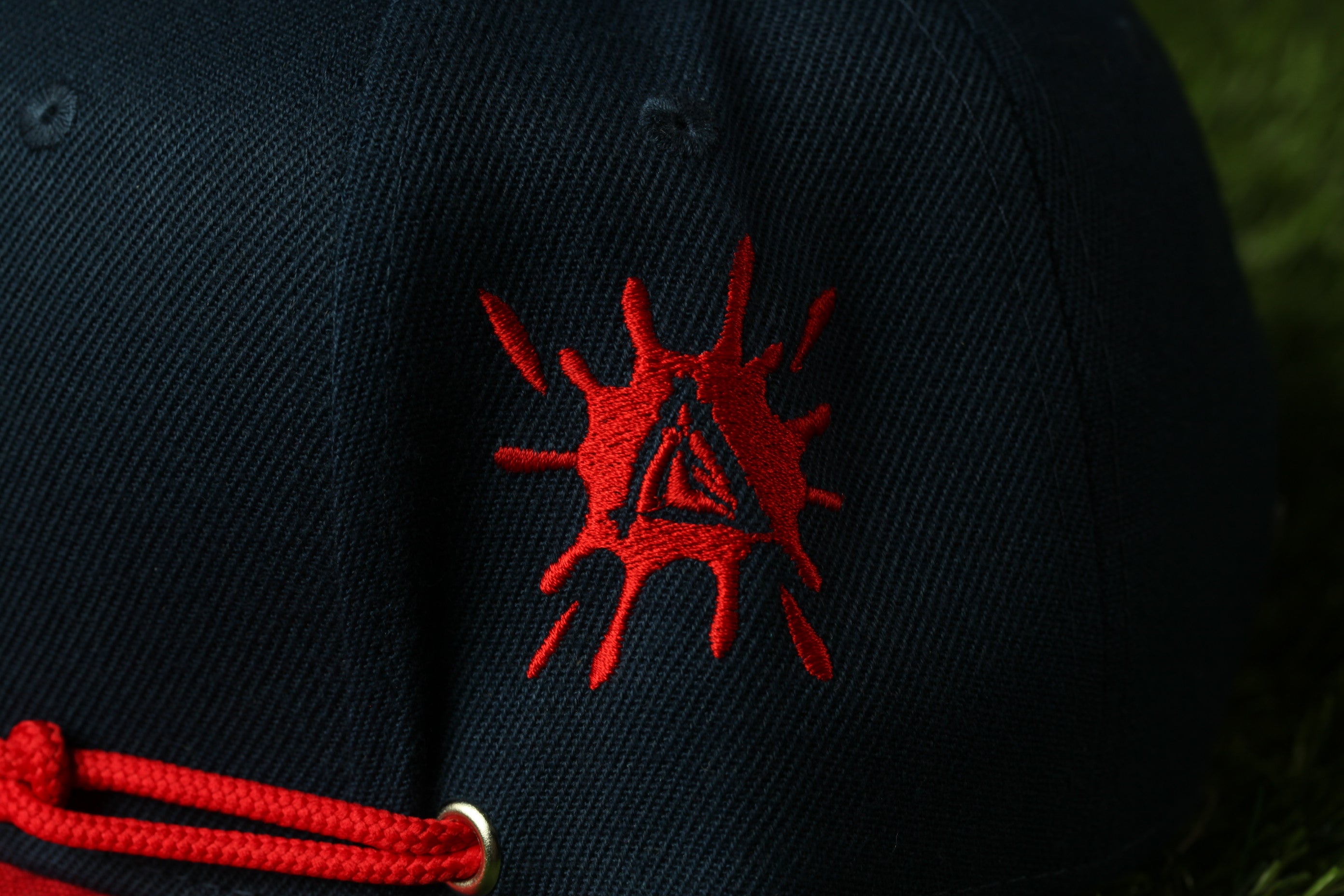A close-up view of a dark blue baseball cap with a red splatter design on the front.