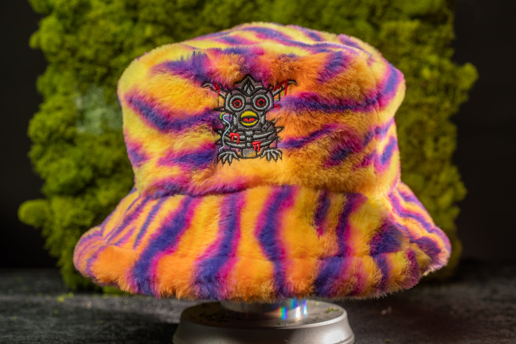 A colorful, fuzzy bucket hat with a unique design featuring a small, stylized creature or character on the front.