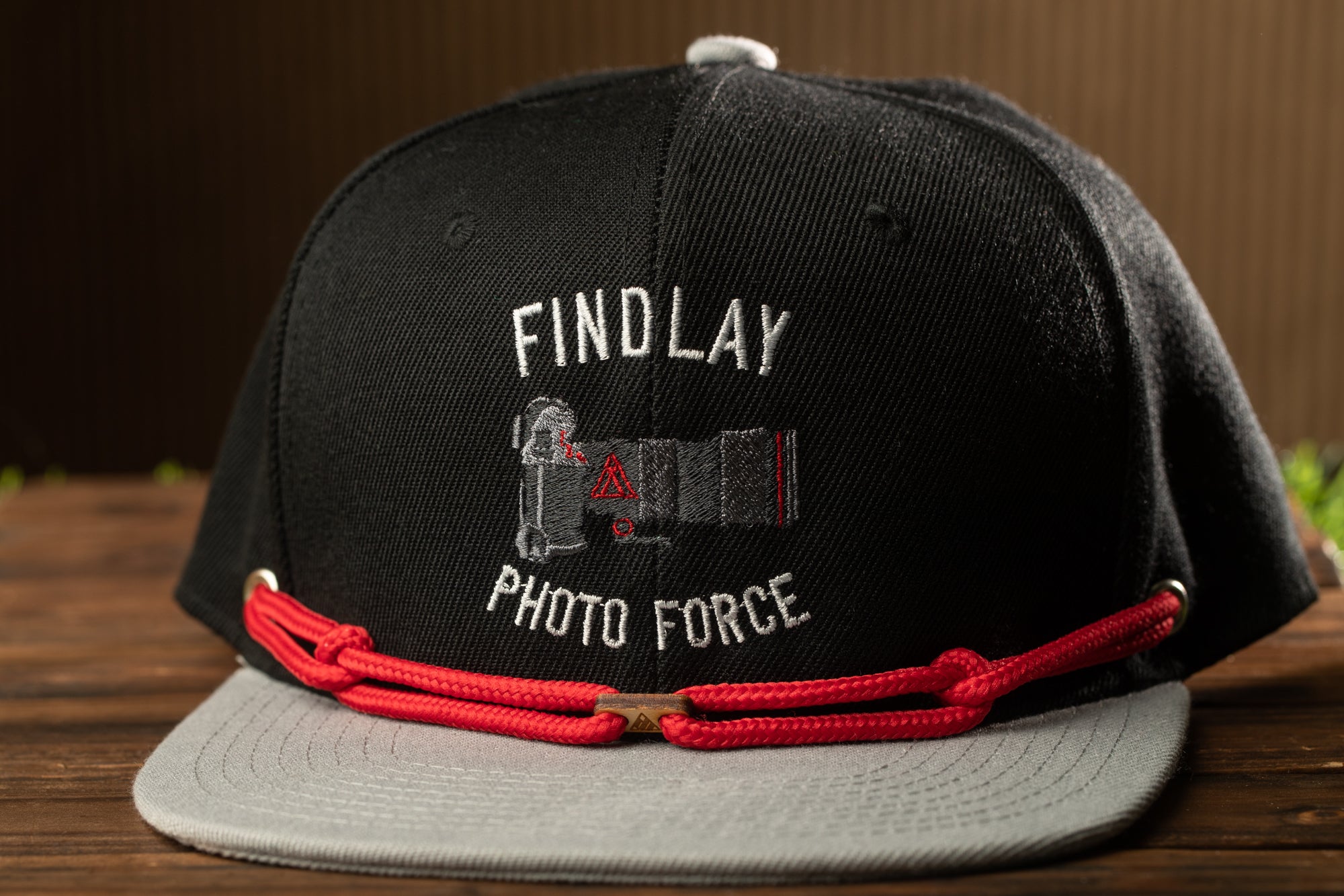 A black baseball cap with a red strap and the text "FINDLAY PHOTO FORCE" printed on it.