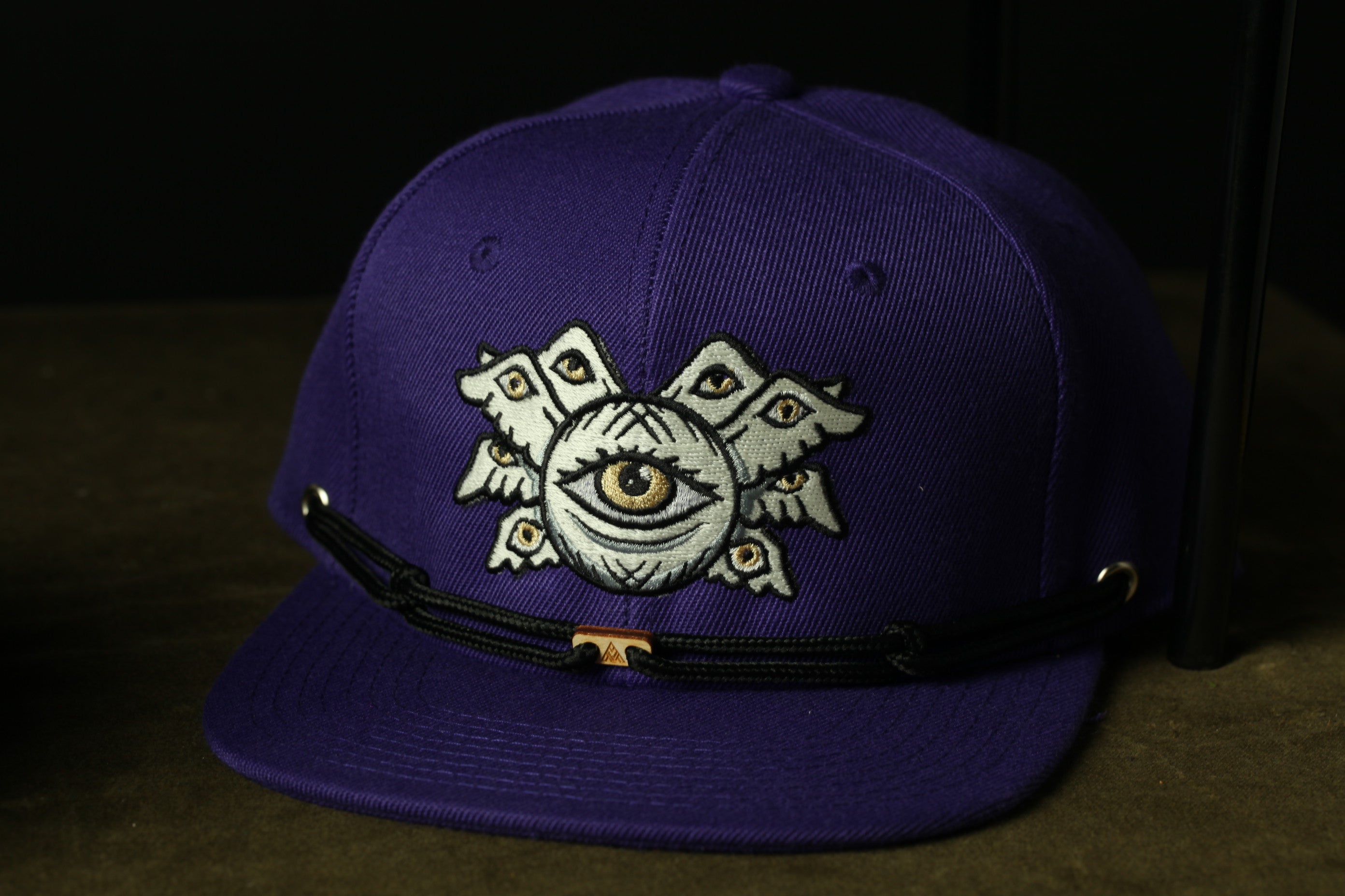 A purple baseball cap with an eye design on the front.