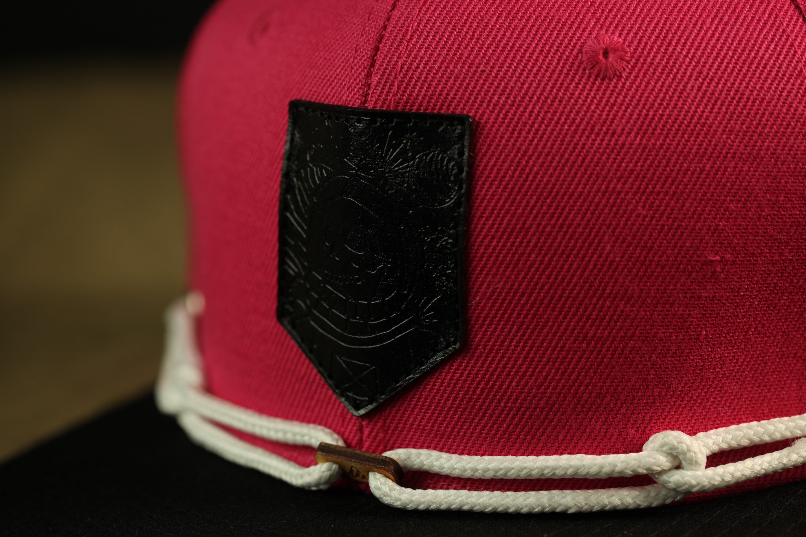 A close-up view of a red baseball cap with a black patch on the front.
