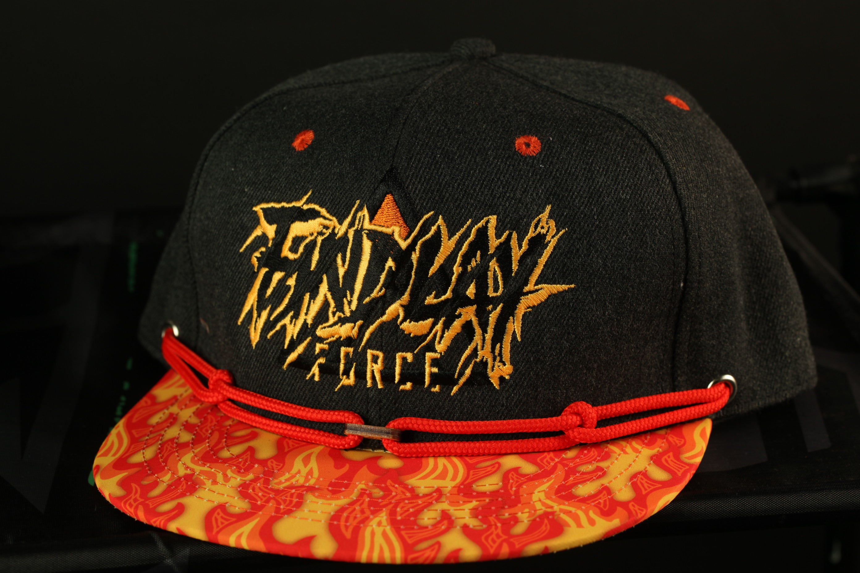 A black baseball cap with a red and yellow patterned brim, featuring the text "FANDY FORCE" in a stylized font.