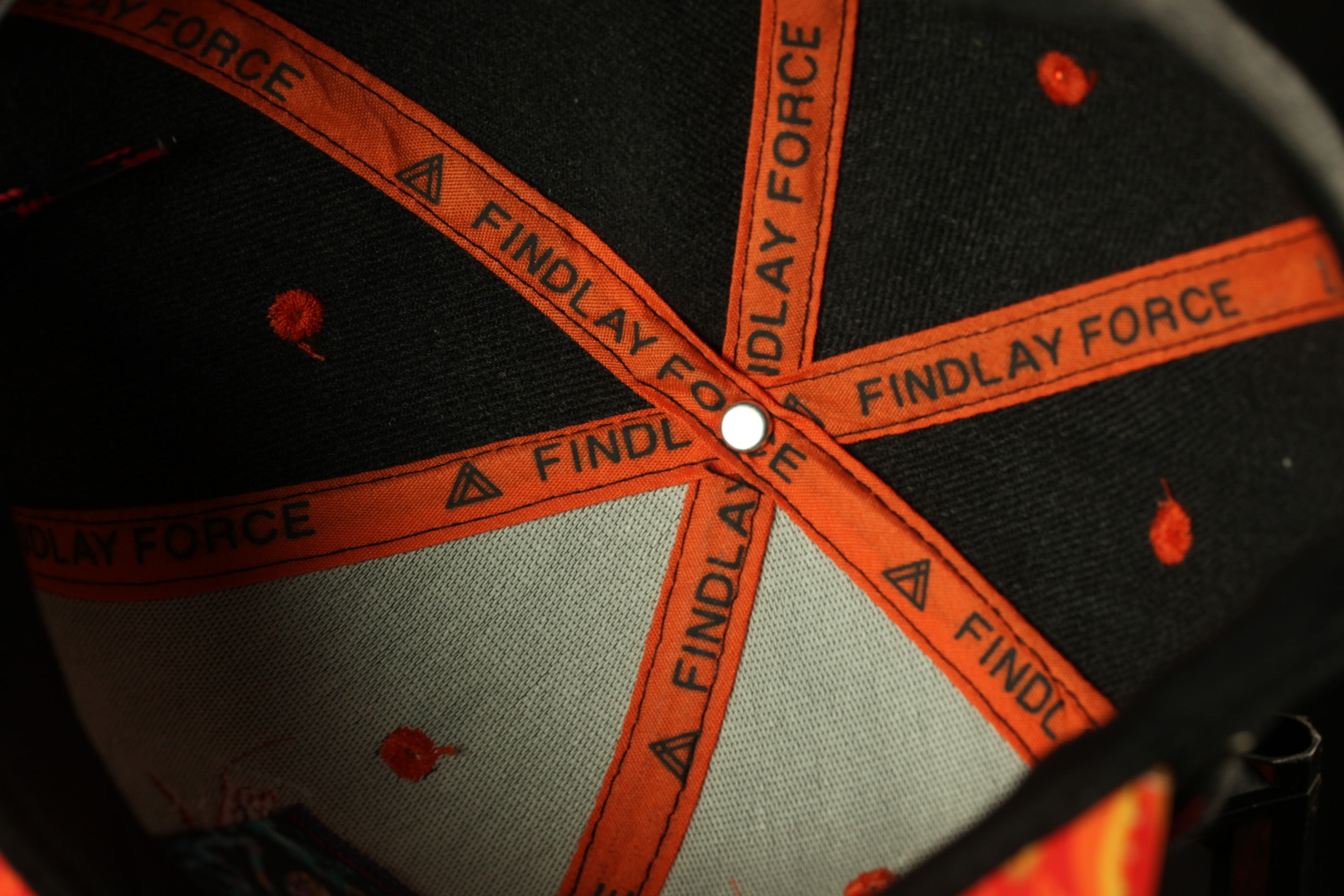 the interior of a baseball cap, specifically focusing on the brim and the orange stitching.