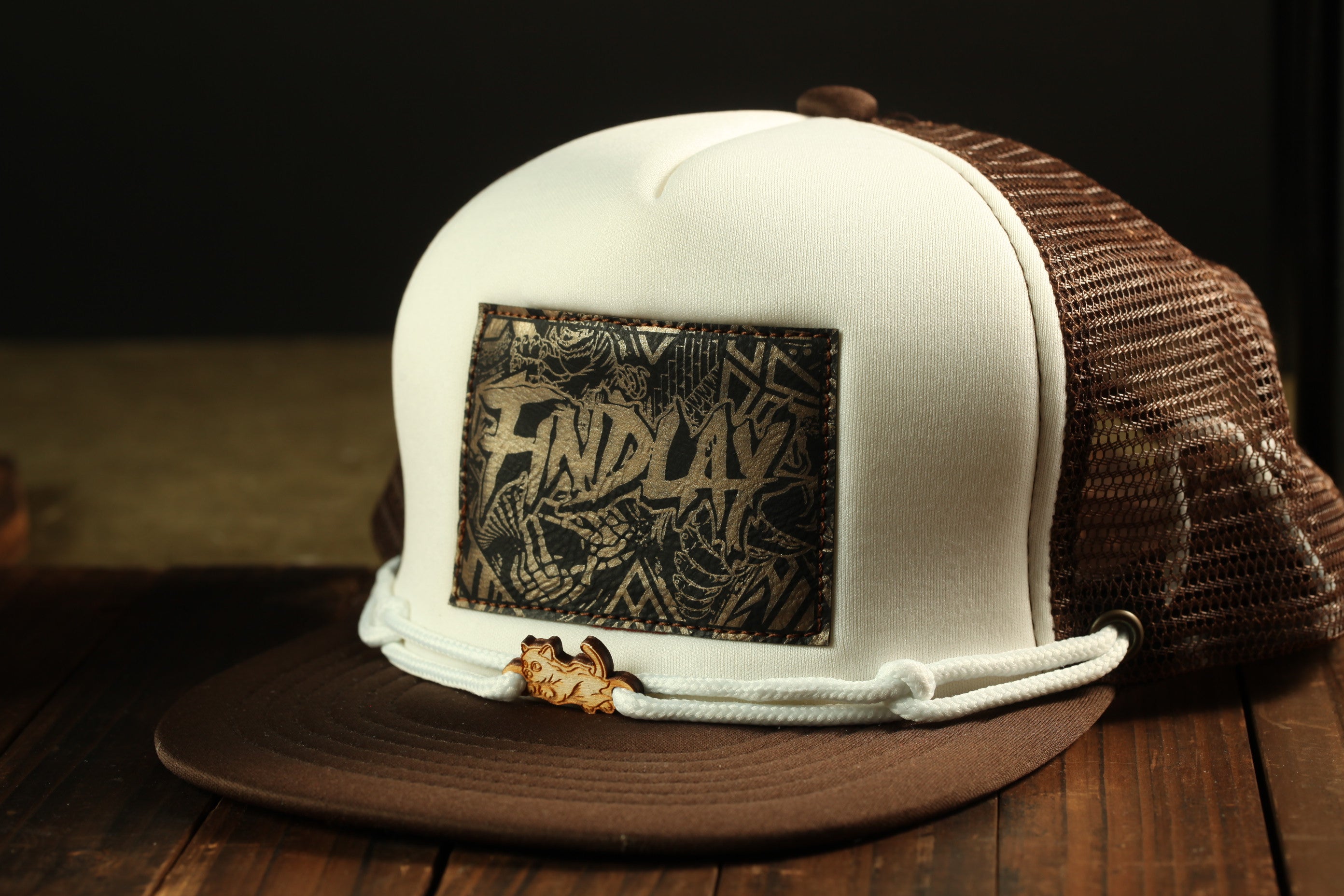A white baseball cap with a brown mesh back, featuring a patch with the word "FIND" printed on it.