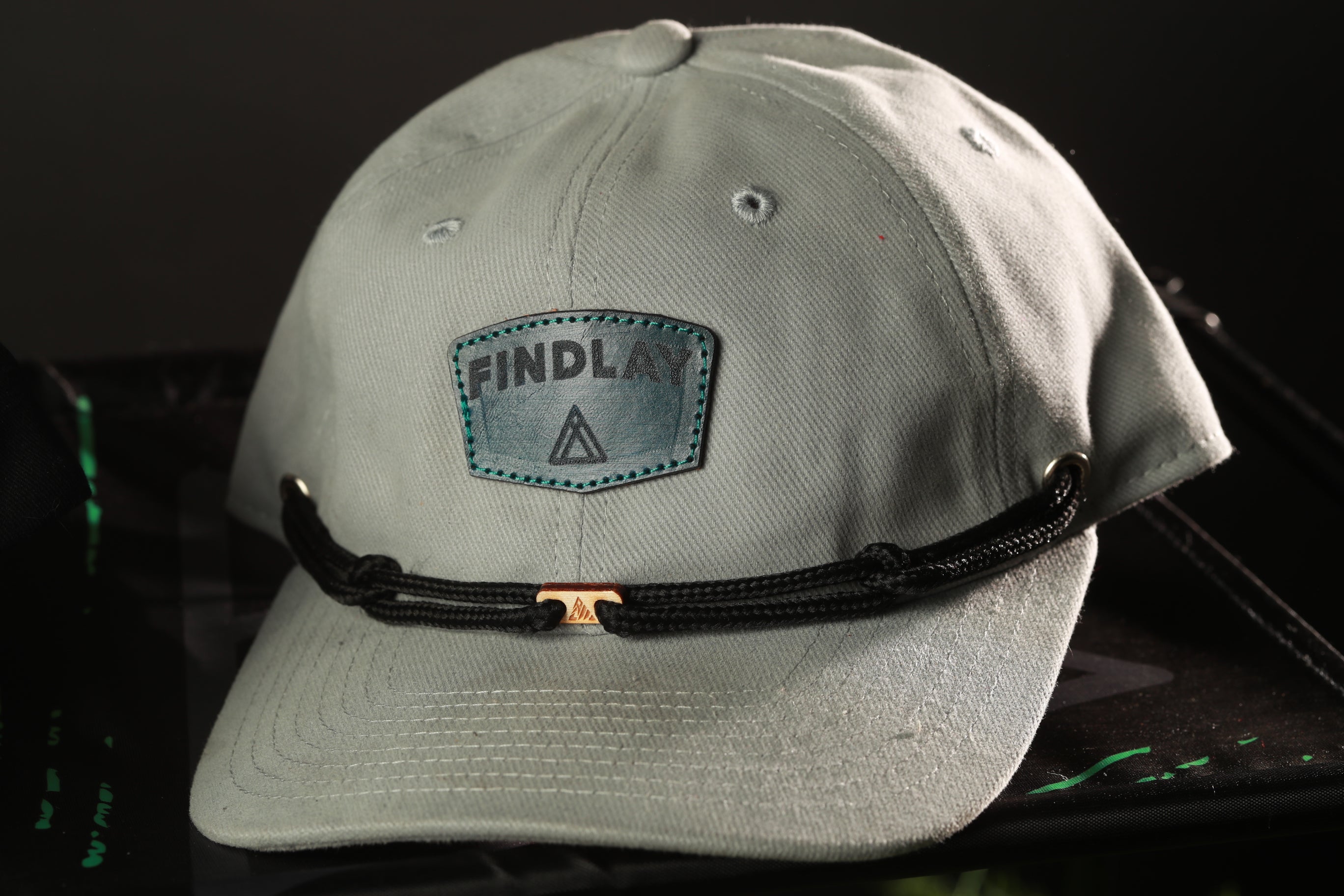A gray baseball cap with a black strap and a patch on the front that says "FINDLAY".