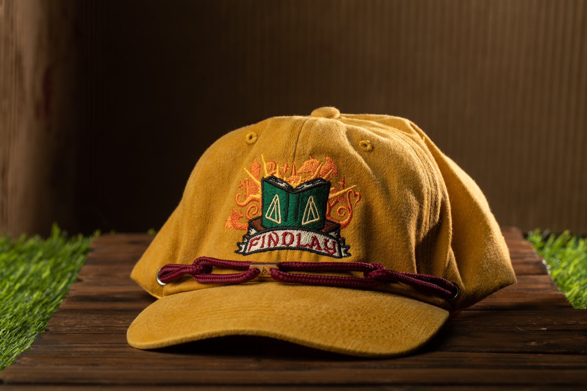 A yellow baseball cap with a green and orange design on the front, sitting on a wooden surface.