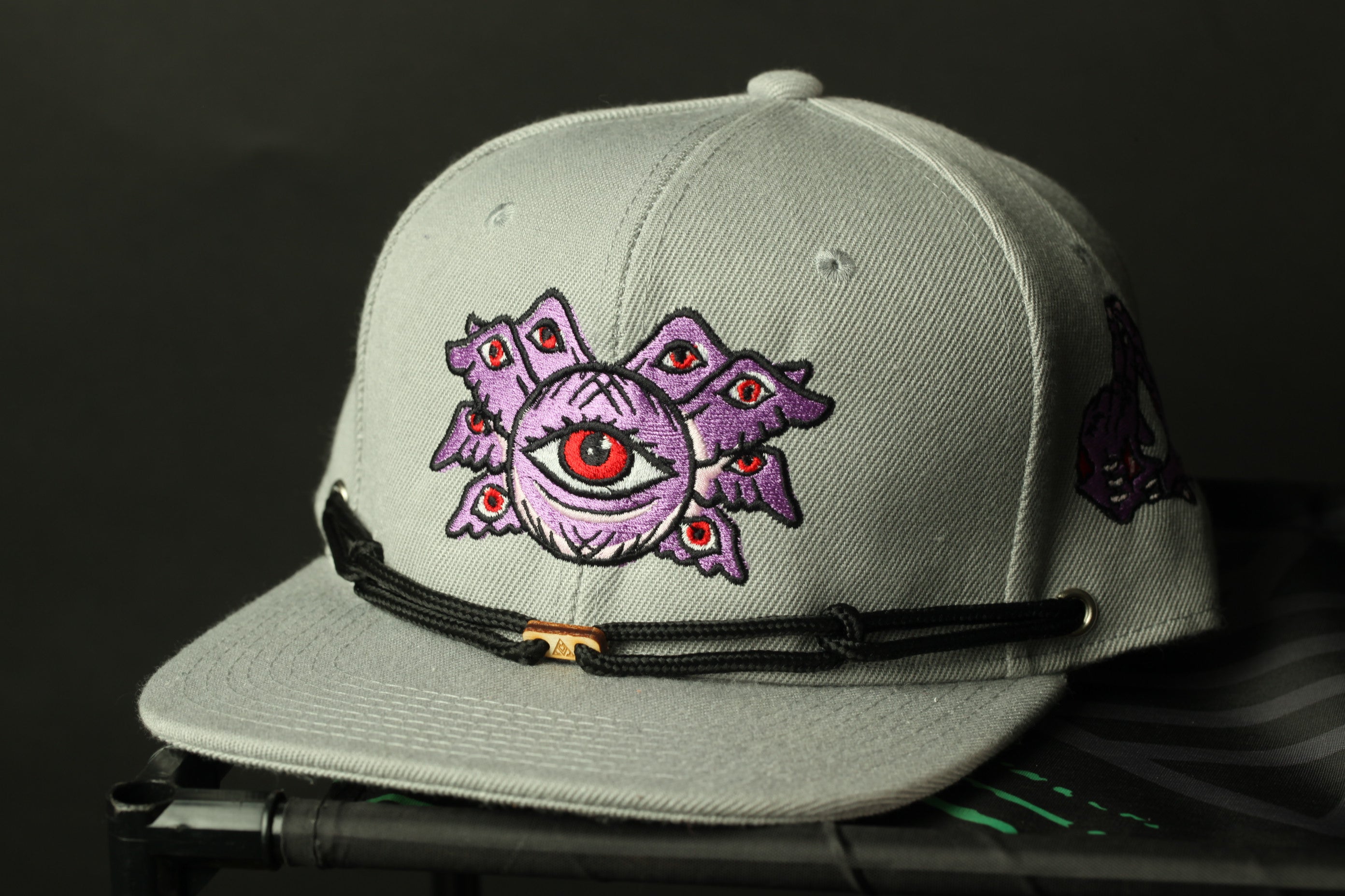 A gray baseball cap with a purple eye design on the front.