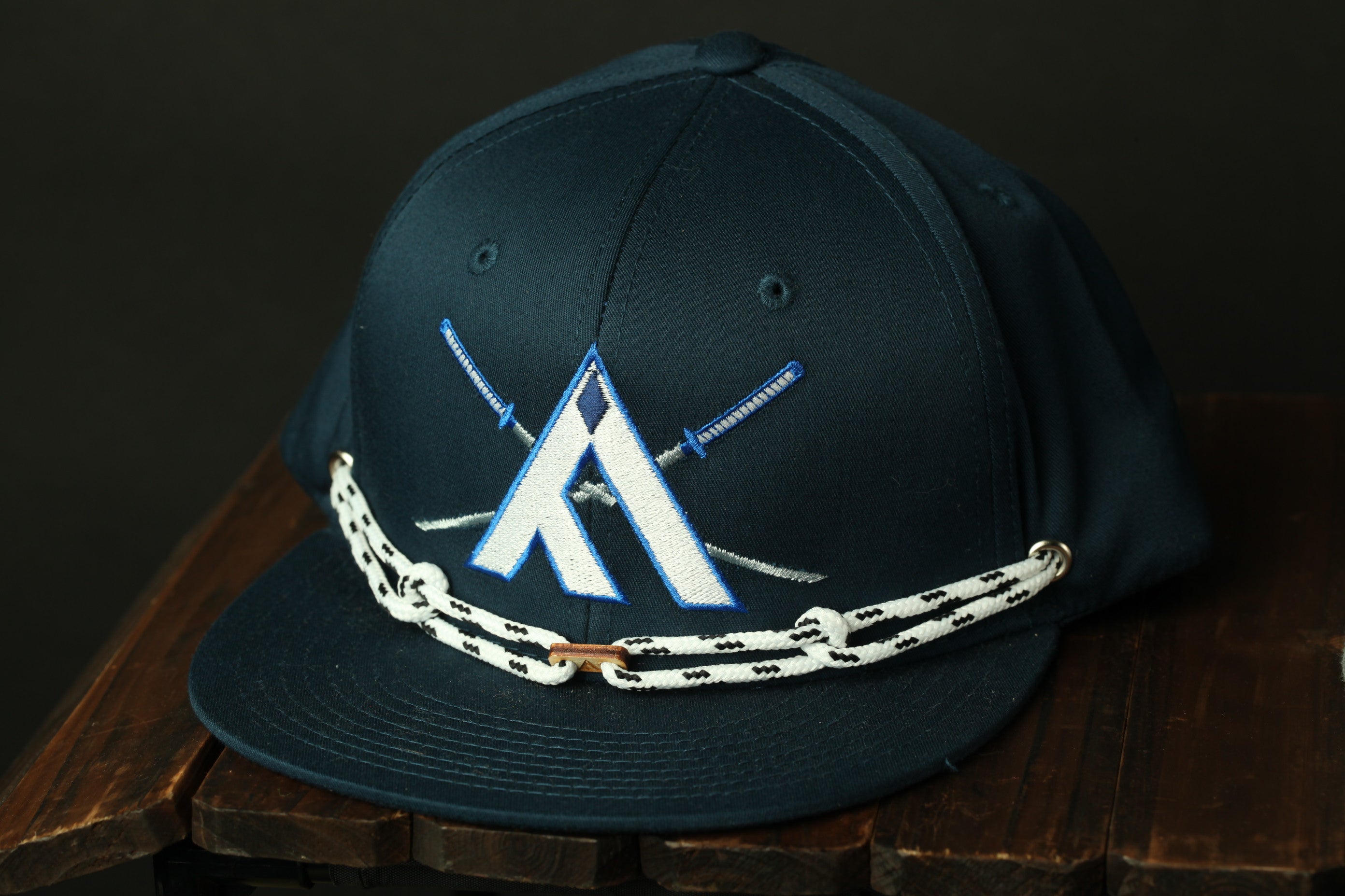 A navy blue baseball cap with a white and blue logo on the front, sitting on a wooden surface.