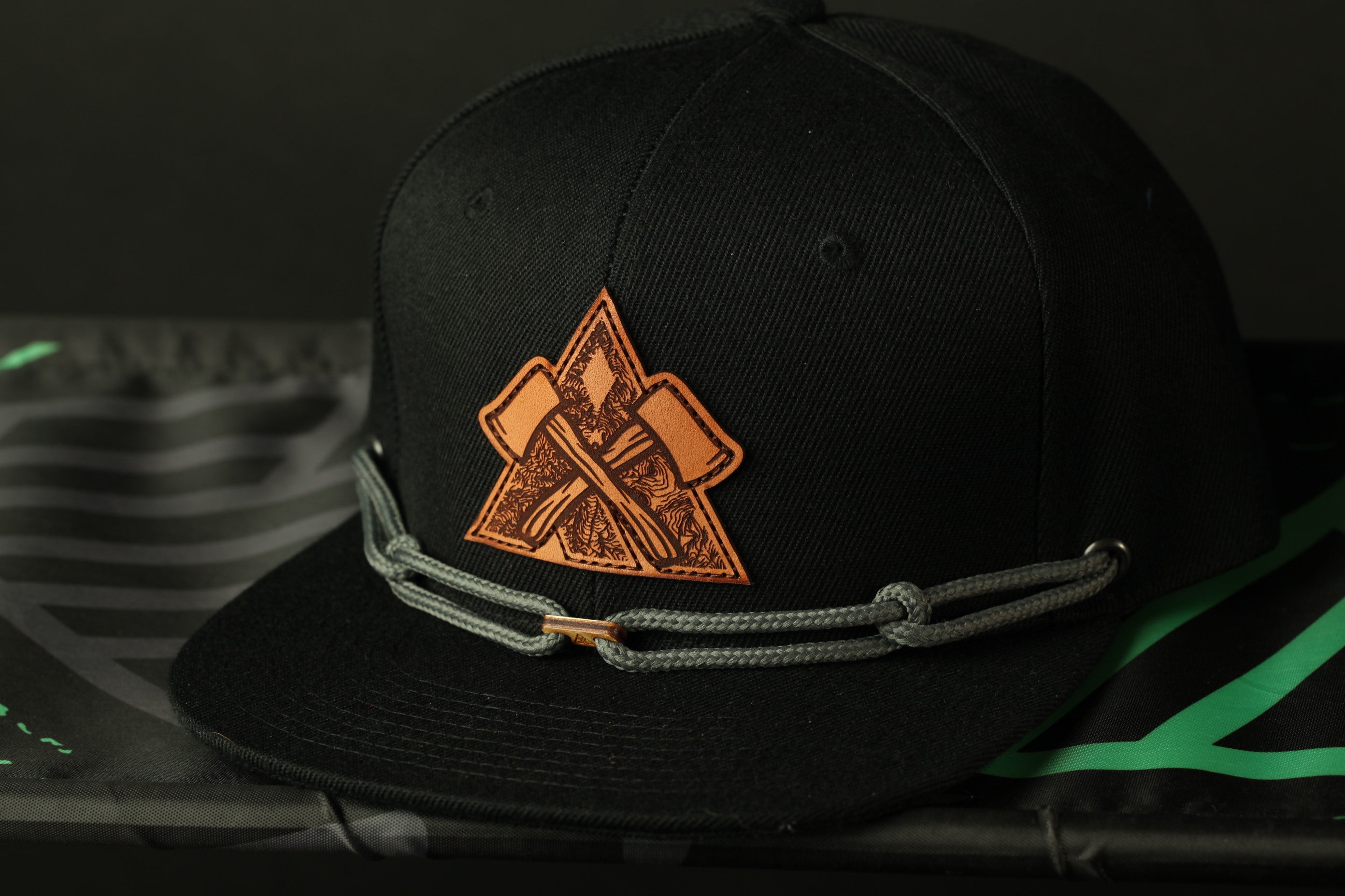 A black baseball cap with a distinctive orange and black logo on the front, resting on a black surface.