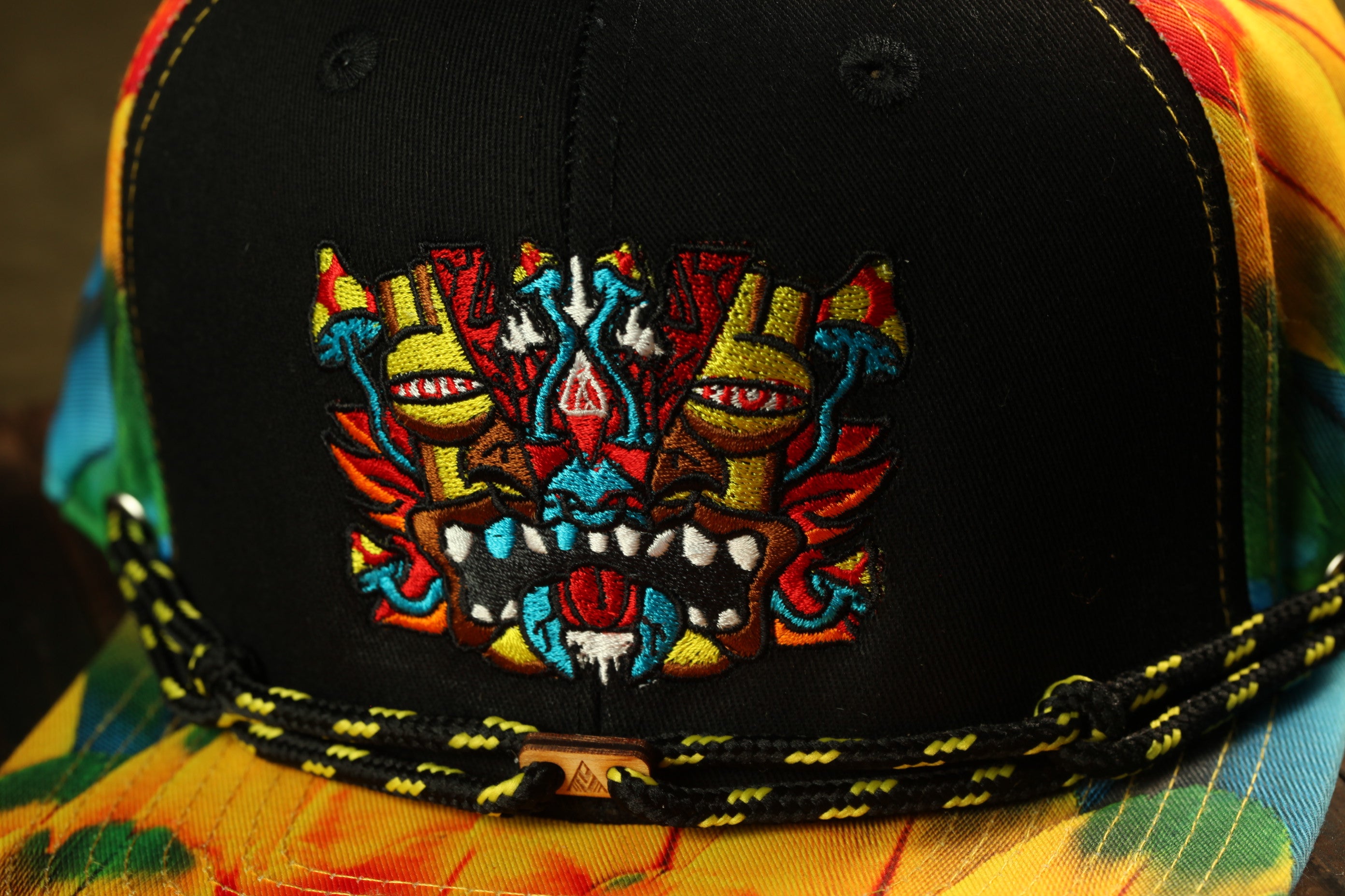 A close-up view of a colorful baseball cap with a detailed embroidered design on the front.
