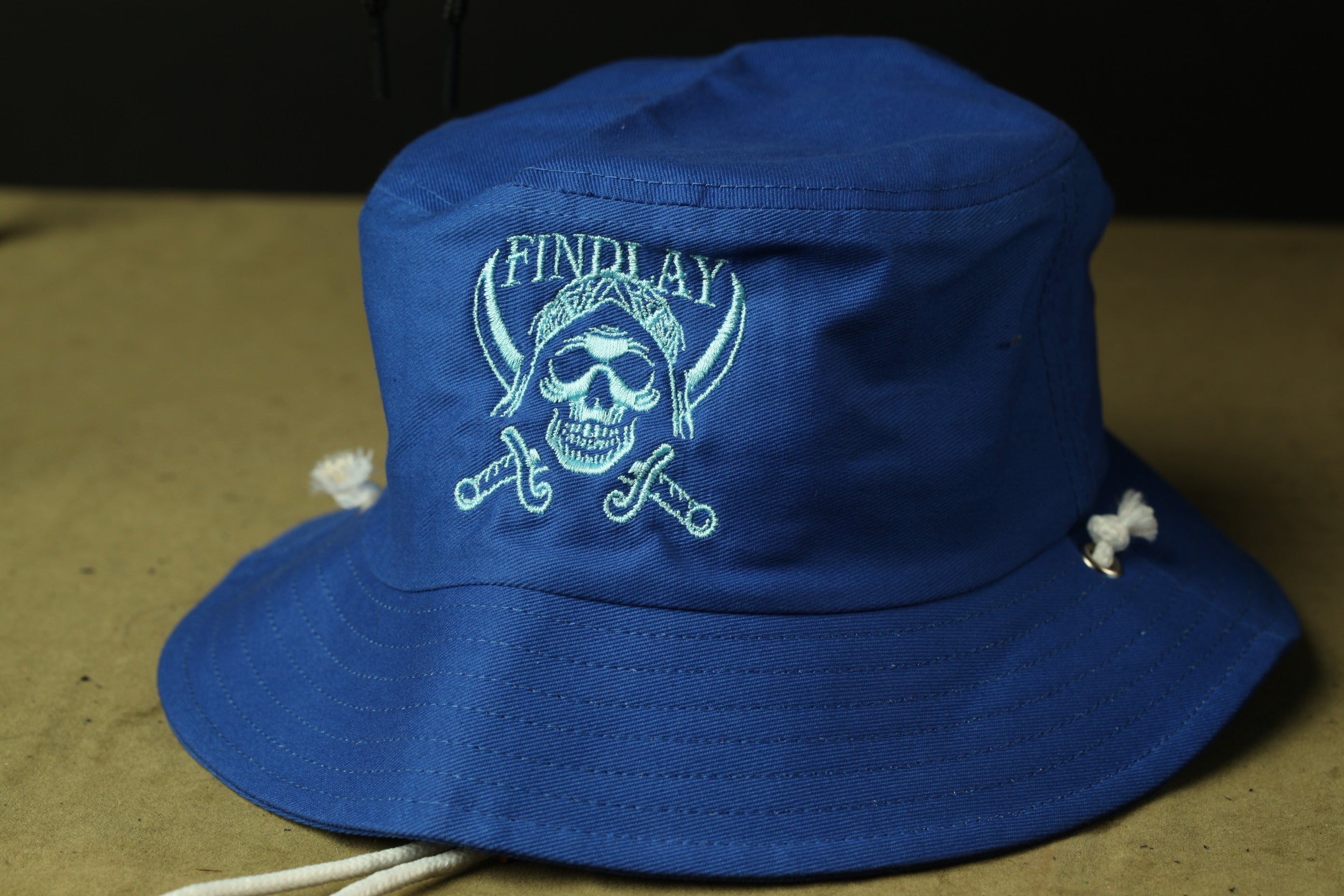 A blue bucket hat with a skull and crossbones design on the front.
