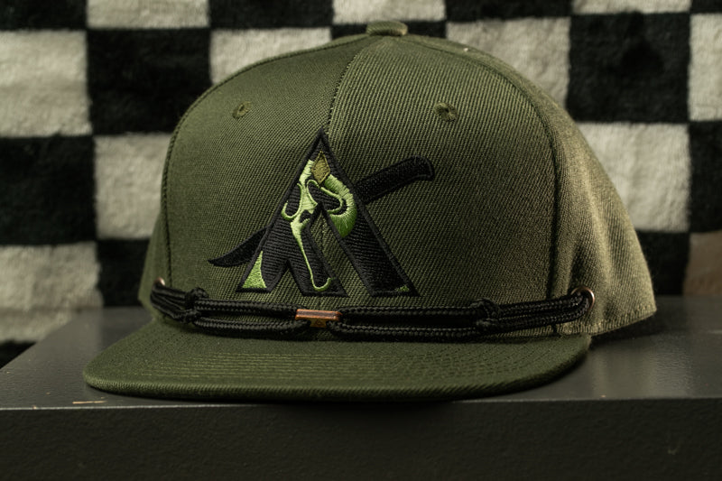 A green baseball cap with a black logo on it, placed on a surface against a checkered background.