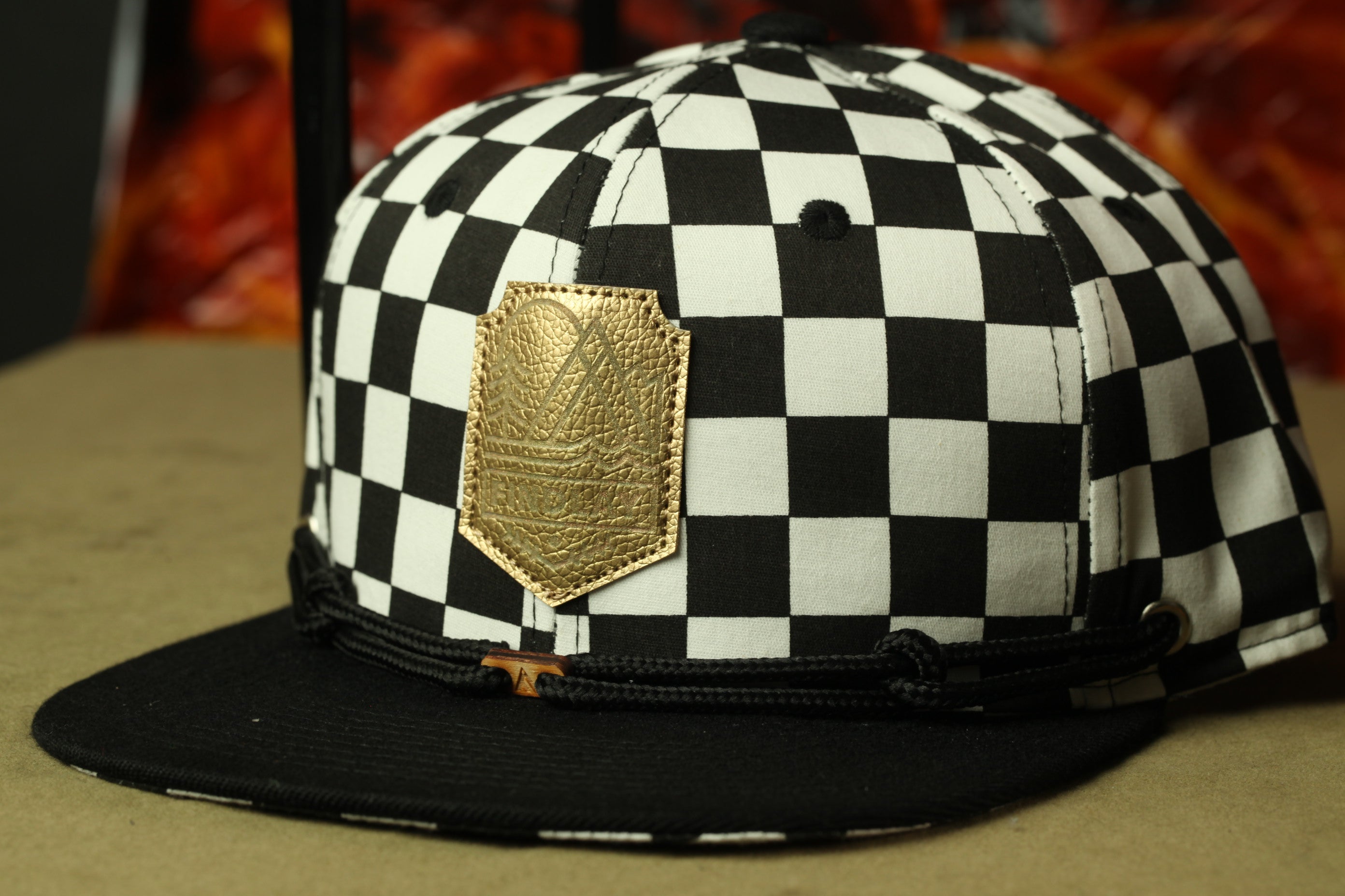 A black and white checkered baseball cap with a gold patch on the front.