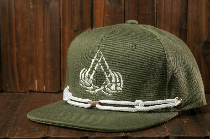 A green baseball cap with a white skull design on the front, resting on a wooden surface.