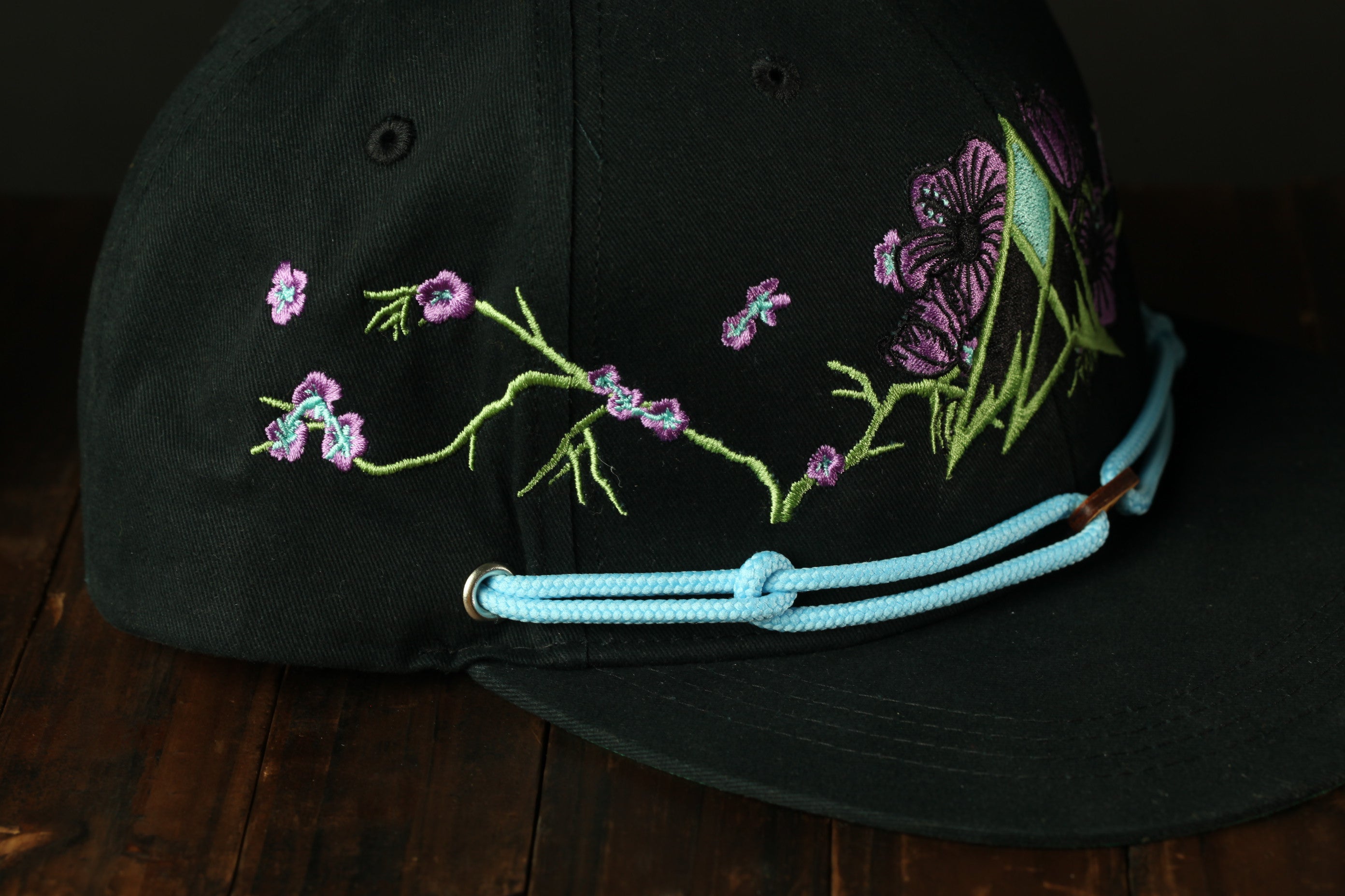 A black baseball cap with a floral embroidered design on the front.