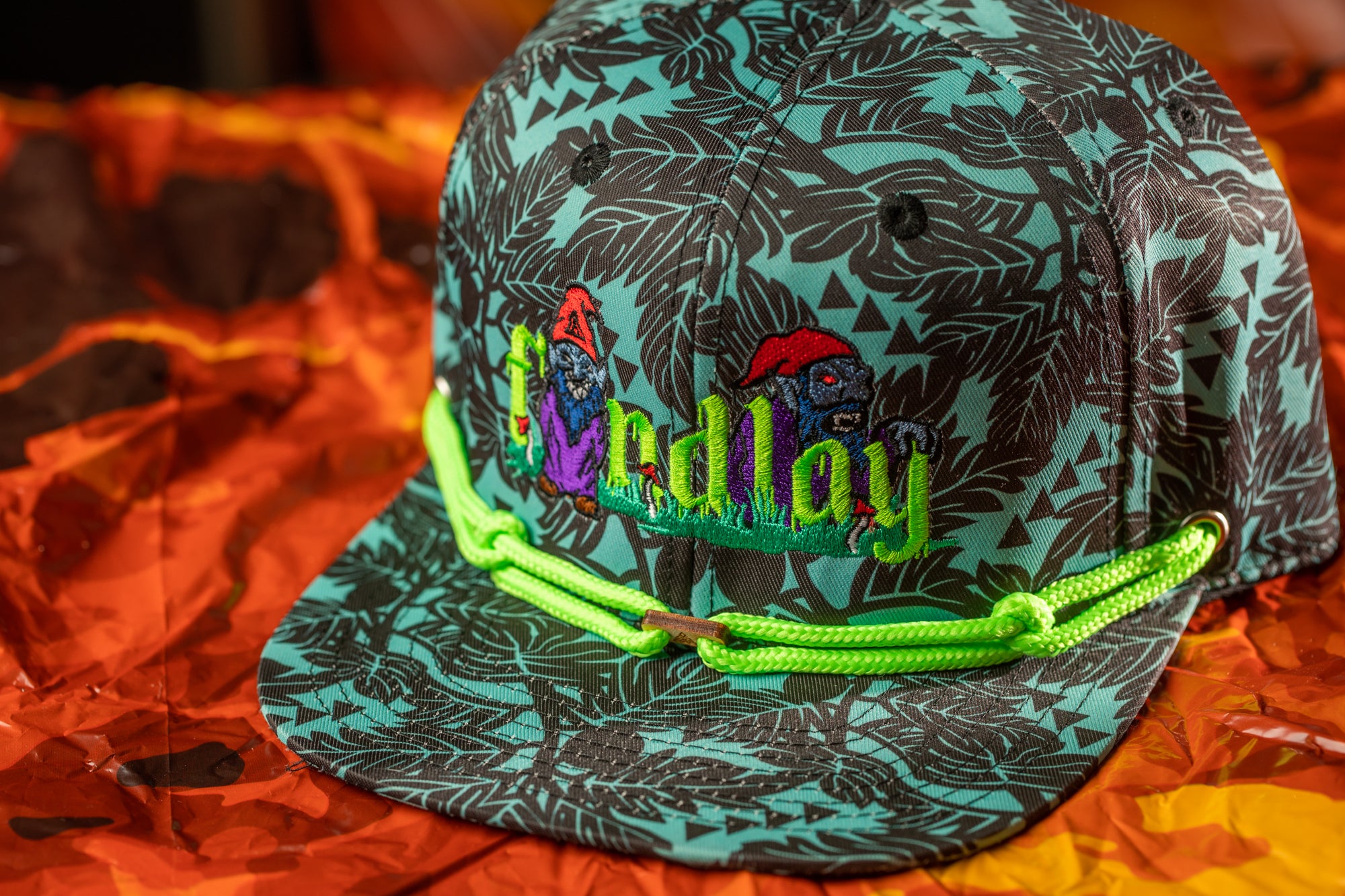 A colorful baseball cap with a floral pattern and a green string around the brim.