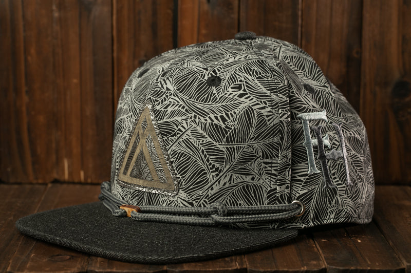 A black and white patterned baseball cap with a triangular logo on the front, resting on a wooden surface.